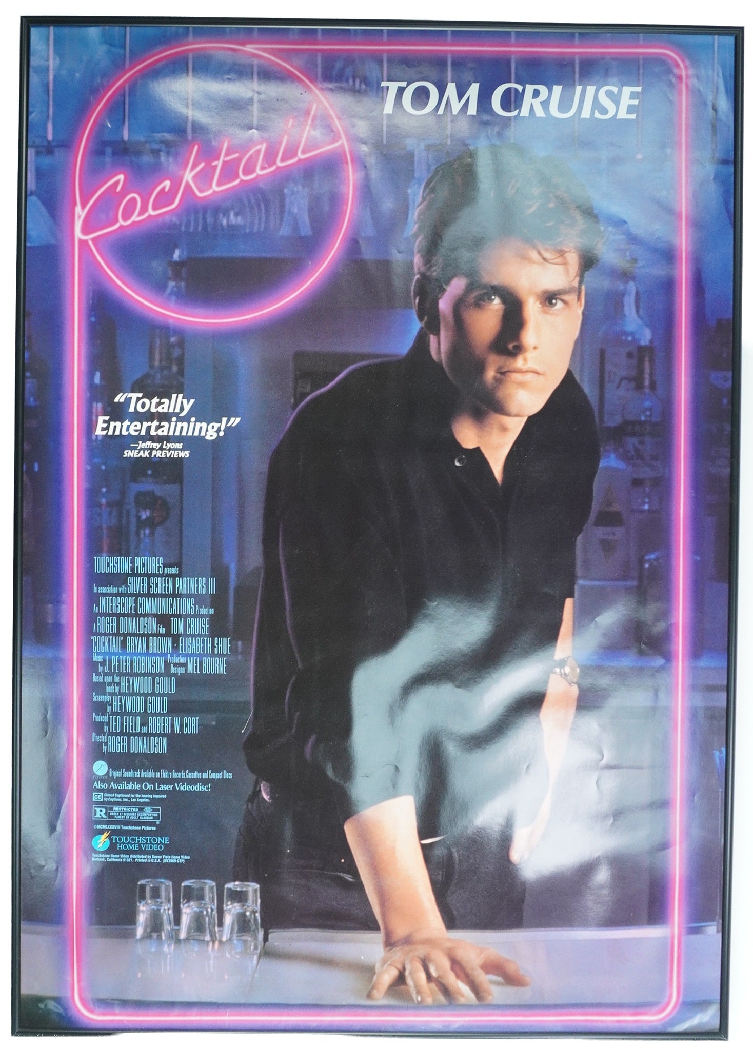 Touchstone Pictures Framed Movie Poster, Cocktail: A framed movie poster for the 1988 Touchstone Pictures film 'Cocktail'. The movie stars Tom Cruise, Bryan Brown, and Elisabeth Shue and is directed by Roger Donaldson. The poster is housed in a black 