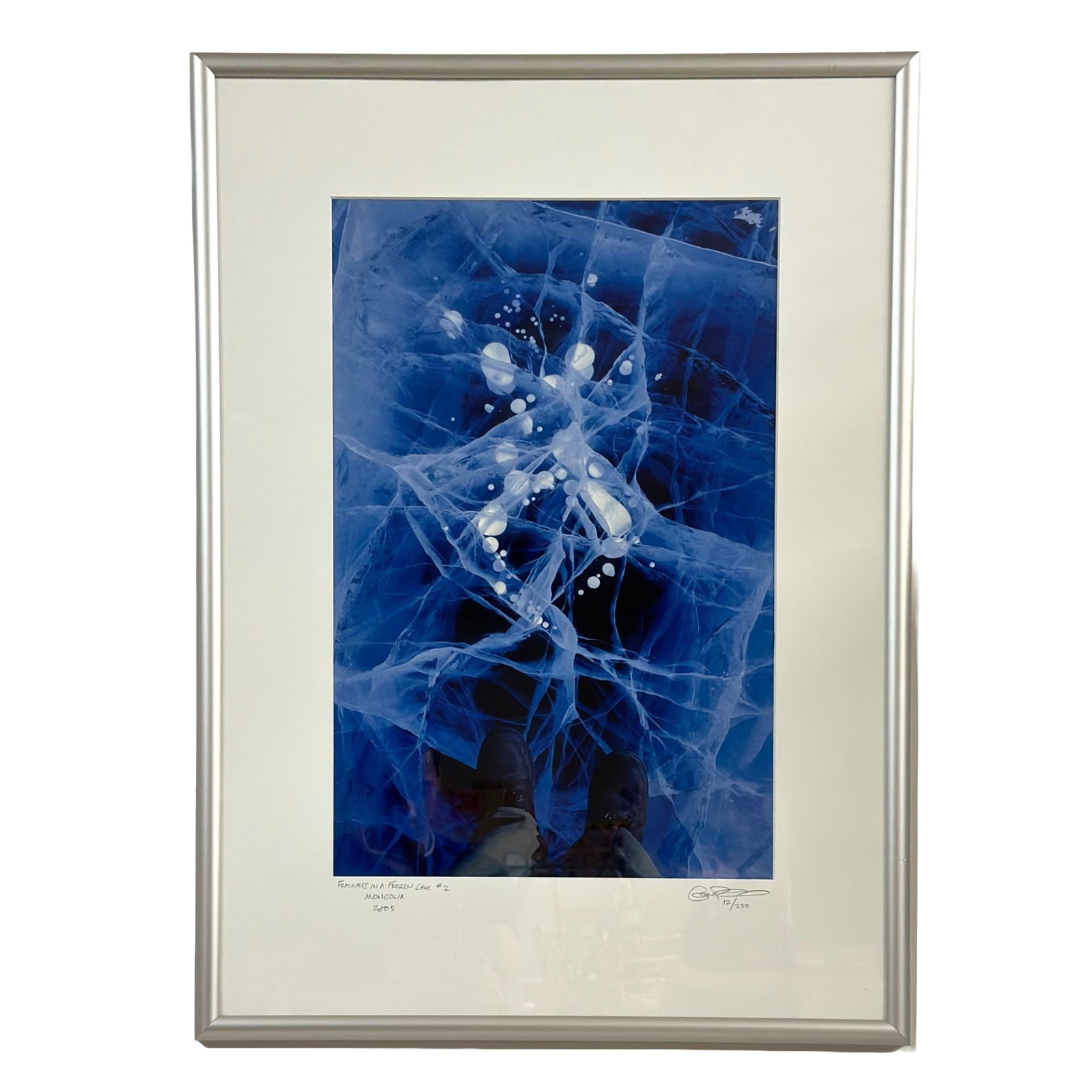 Gene Pembroke, Fractures in a Frozen Lake #2, Mongolia, 2005, Limited Edition Print: This color photograph by Gene Pembroke, titled Fractures in a Frozen Lake #2, is a limited edition print from 2005. The image is composed from a first-person perspective, showing a pair of brown boots