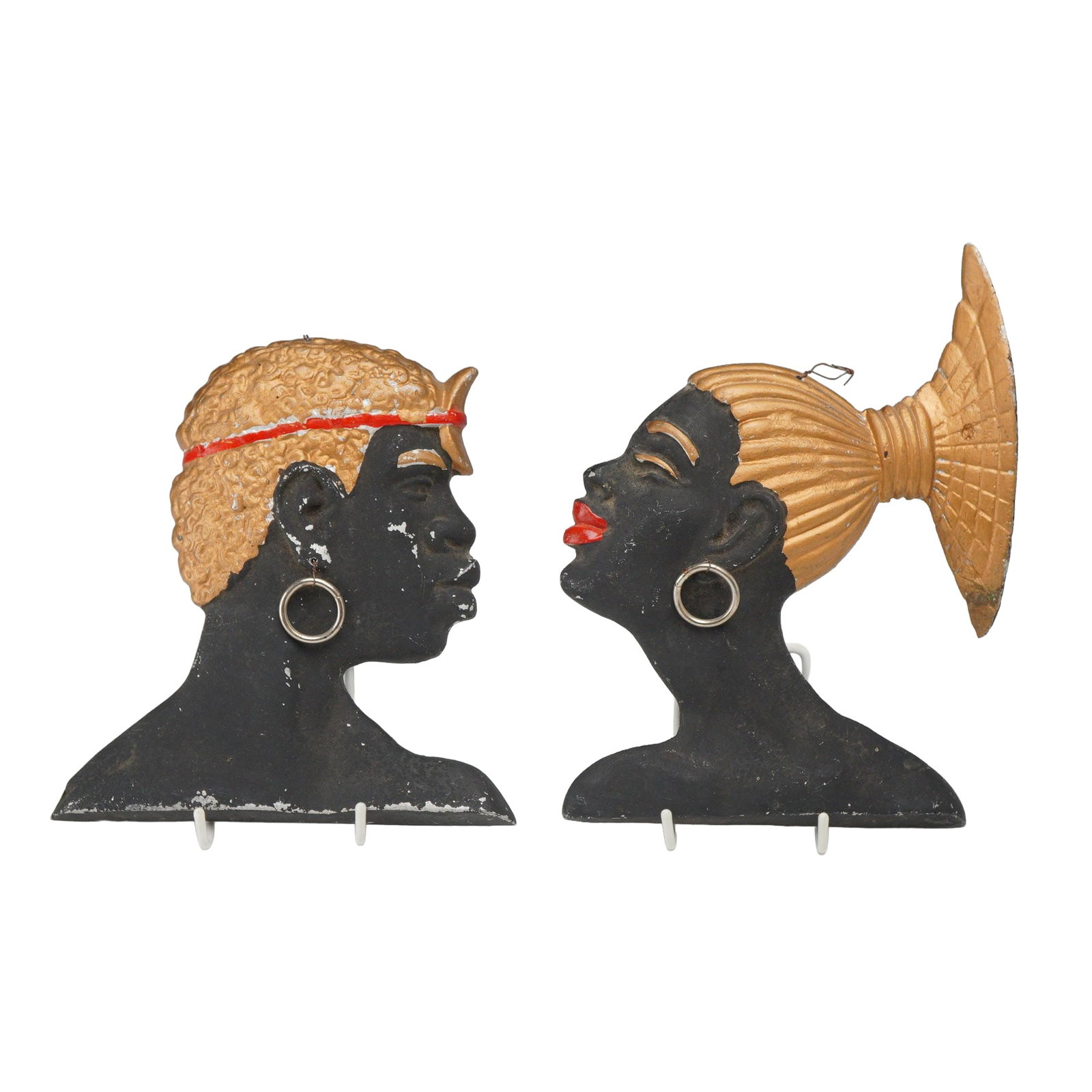 Pair of Mid-Century Modern Painted Cast Aluminum Africana Wall Decorations: A pair of profile wall plaques depicting an African man and woman in a Mid-Century Modern aesthetic. These pieces are constructed from cast aluminum with a cold-painted finish. The male figure is depi