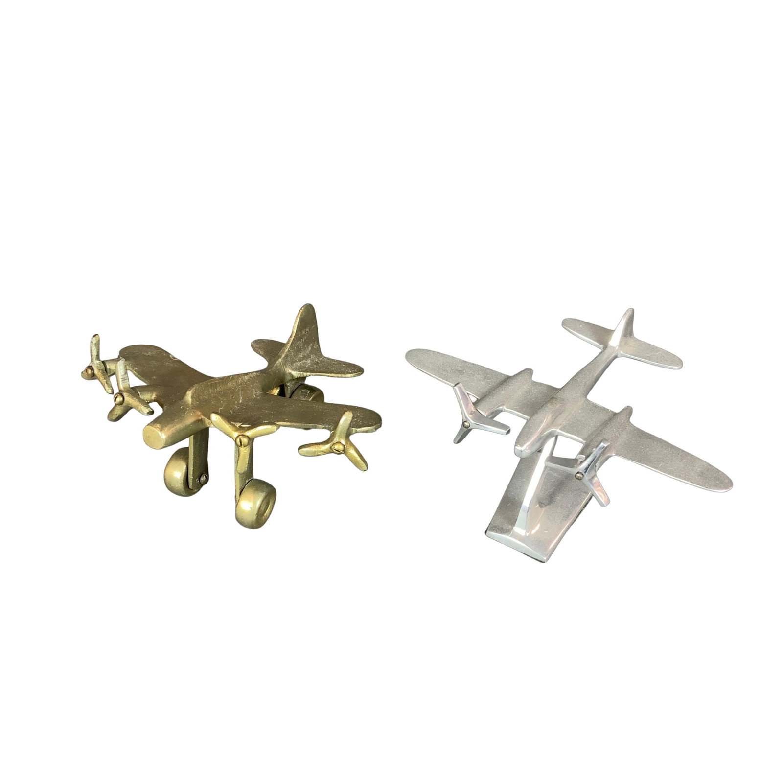 2pc Gold Tone and Silver Tone Metal Model Planes: This lot contains two metal plane decorative figures. The first model depicts a twin-engine propeller aircraft in a mid-century modern style, reminiscent of a Lockheed Electra. It is made of polished 