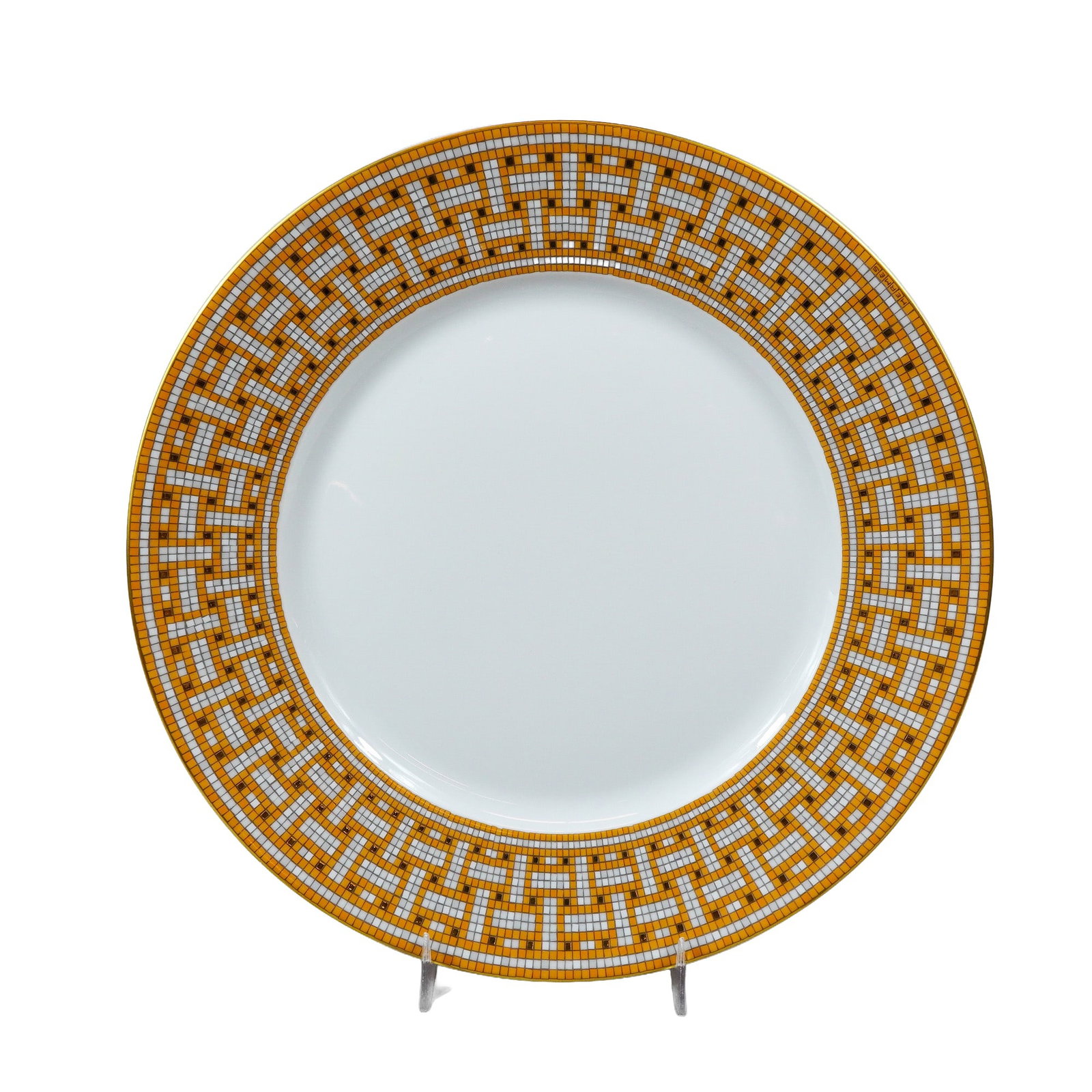 Hermes Mosaique Au 24 Gold Porcelain Dinner Plate: Hermes. Fine white porcelain dinner plate in the Mosaique Au 24 pattern. The design features a wide geometric mosaic border in shades of ochre orange, gray, and white with gold-toned tiles, referencin