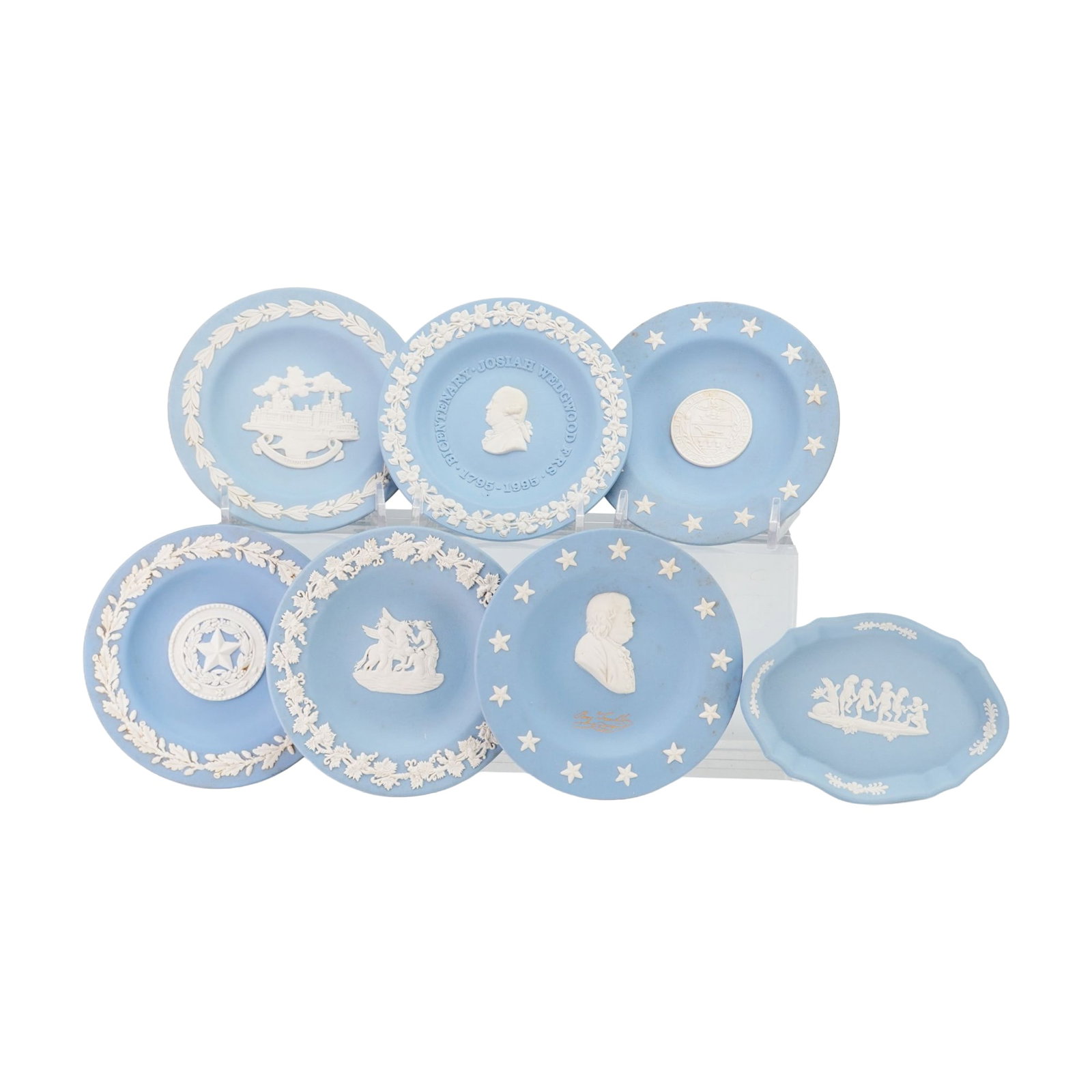 7pc Wedgwood Blue Jasperware Decorative Dishes and Sweetmeat Plates: A collection of seven Wedgwood blue jasperware decorative pieces featuring various classical and commemorative motifs. This assortment includes six circular sweetmeat dishes and one oval scalloped
