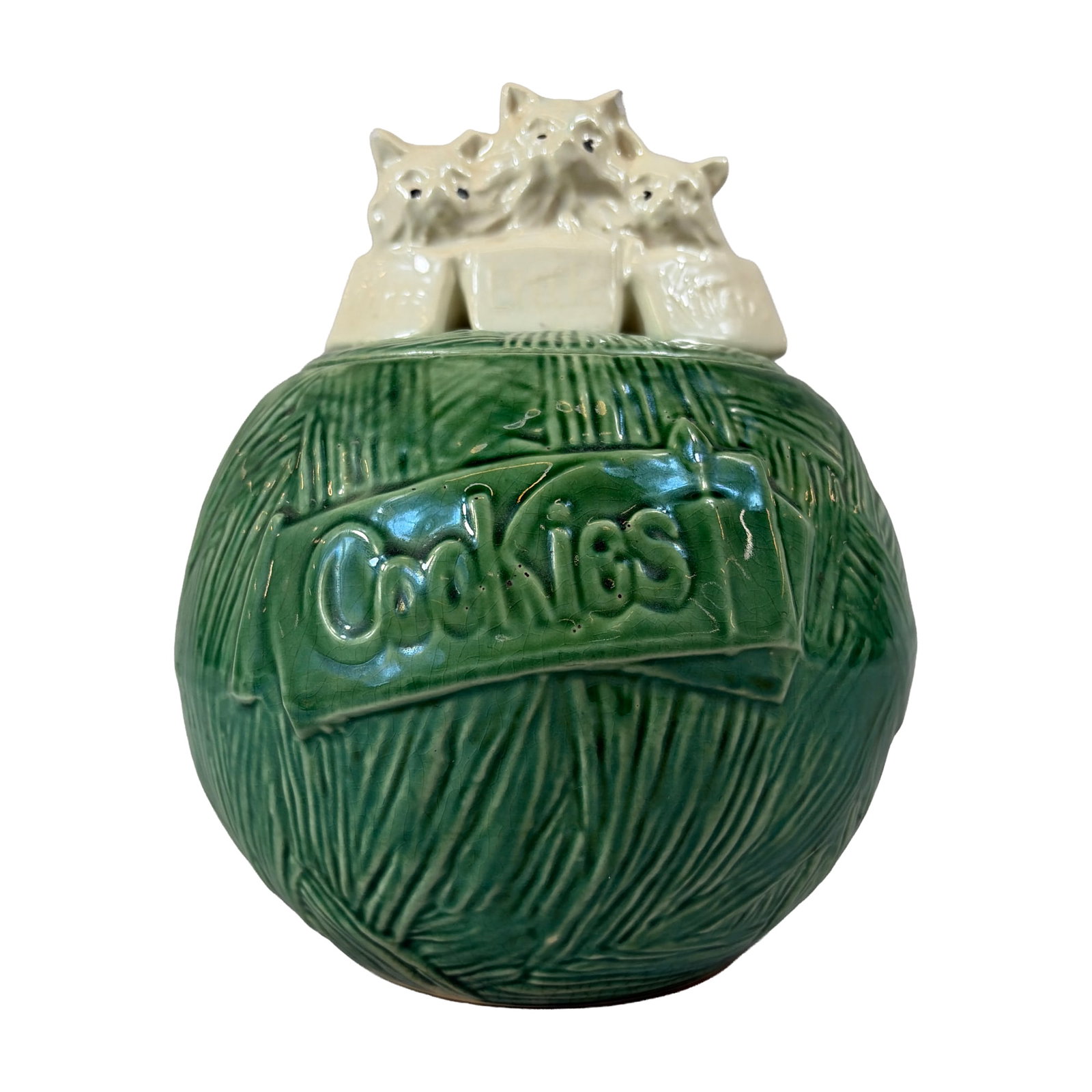 McCoy Green Ball of Yarn Kitten Cookie Jar: Glazed earthenware spherical jar molded with a textured yarn pattern and finished in high-gloss green. Features a relief-molded banner to the front reading Cookies in script. The lid is surmounted by 