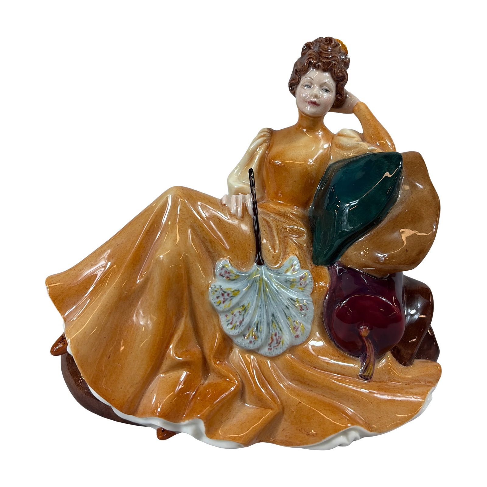 Royal Doulton 2004 Trial Piece Porcelain Figurine, 2 of 3: Royal Doulton glazed porcelain figurine depicts a seated woman in an apricot-colored gown holding a floral-decorated fan, reclining against a pile of cushions in brown, burgundy, and deep green glaze.