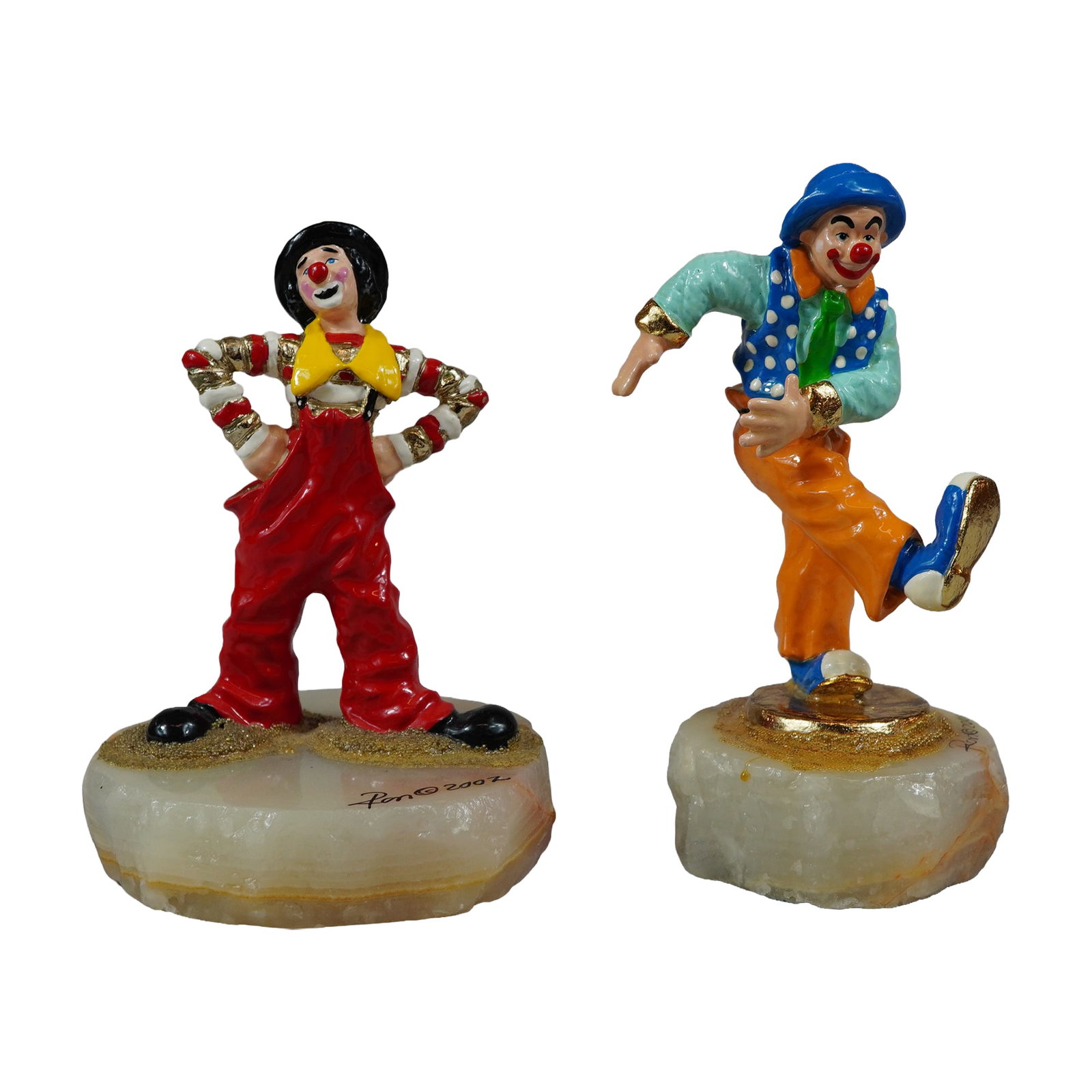 2pc Ron Lee Signed Onyx Base Clown Sculptures: Ron Lee (American, 1947-2017). Pair of hand-painted metal clown sculptures with 24kt gold-plated accents. One figure portrays a clown in a standing pose wearing red overalls and a black bowler hat, da