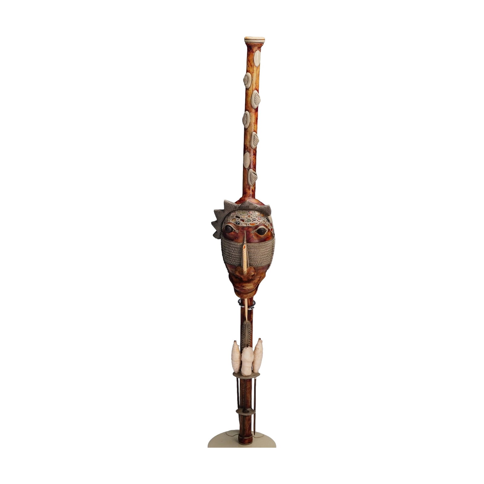 African Style Carved Wooden Staff Sculpture: Striking carved wooden staff sculpture featuring an elaborate mask face with intricate patterns and raised elements, accented by inset shells and beads, creating expressive eyes and a prominent centra