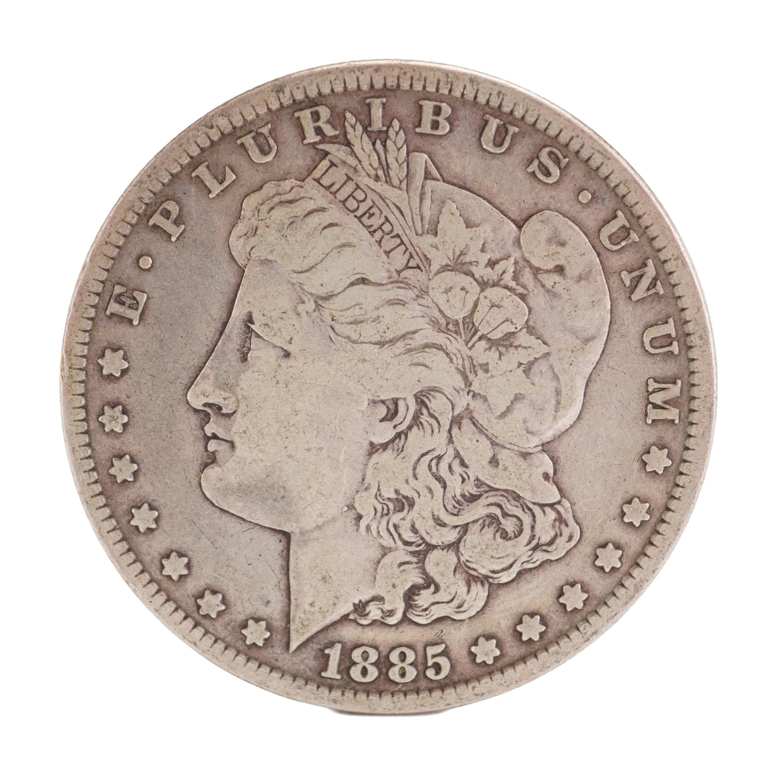 1885 U.S. Morgan Dollar 90% Silver Coin, Circulated: Morgan Dollar with obverse Liberty head, facing left and E PLURIBUS UNUM LIBERTY and date. Revers depicts Eagle holding arrows and an olive branch within wreath. Total weight 26g. Dimensions: 38.1mm D