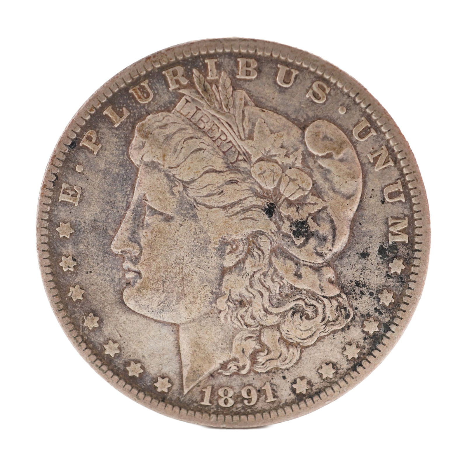 1891 U.S. Morgan Dollar 90% Silver Coin, Circulated: Morgan Dollar with obverse Liberty head, facing left and E PLURIBUS UNUM LIBERTY and date. Revers depicts Eagle holding arrows and an olive branch within wreath. Total weight 28g. Dimensions: 38.1mm D