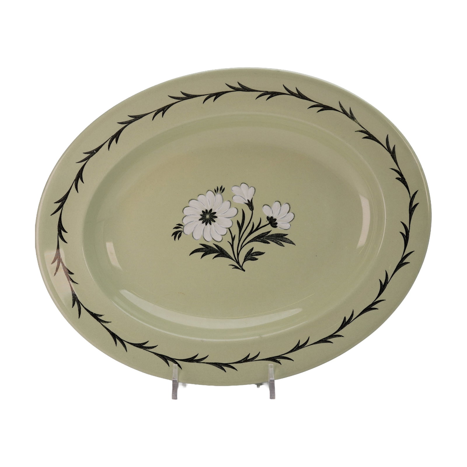 Wedgwood of Etruria & Barlaston Green Oval Serving Bowl, Aster: The platter is finished in a soft sage green glaze and showcases a central black-and-white transfer-printed design of stylized flowers and foliage. Its gently sloping rim is accented with a continuous