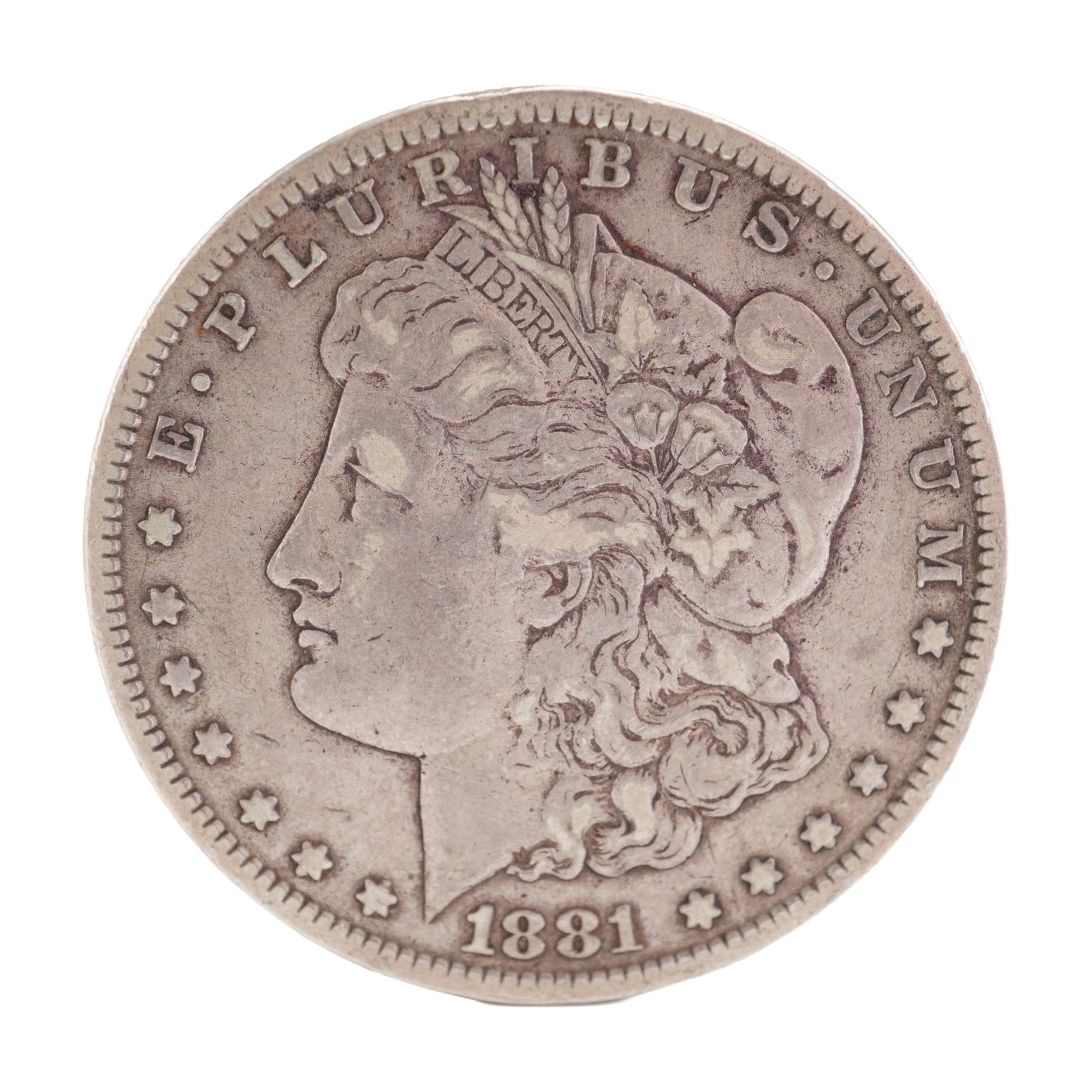 1881 U.S. Morgan Dollar 90% Silver Coin, Circulated: Morgan Dollar with obverse Liberty head, facing left and E PLURIBUS UNUM LIBERTY and date. Revers depicts Eagle holding arrows and an olive branch within wreath. Total weight 26g. Dimensions: 38.1mm D