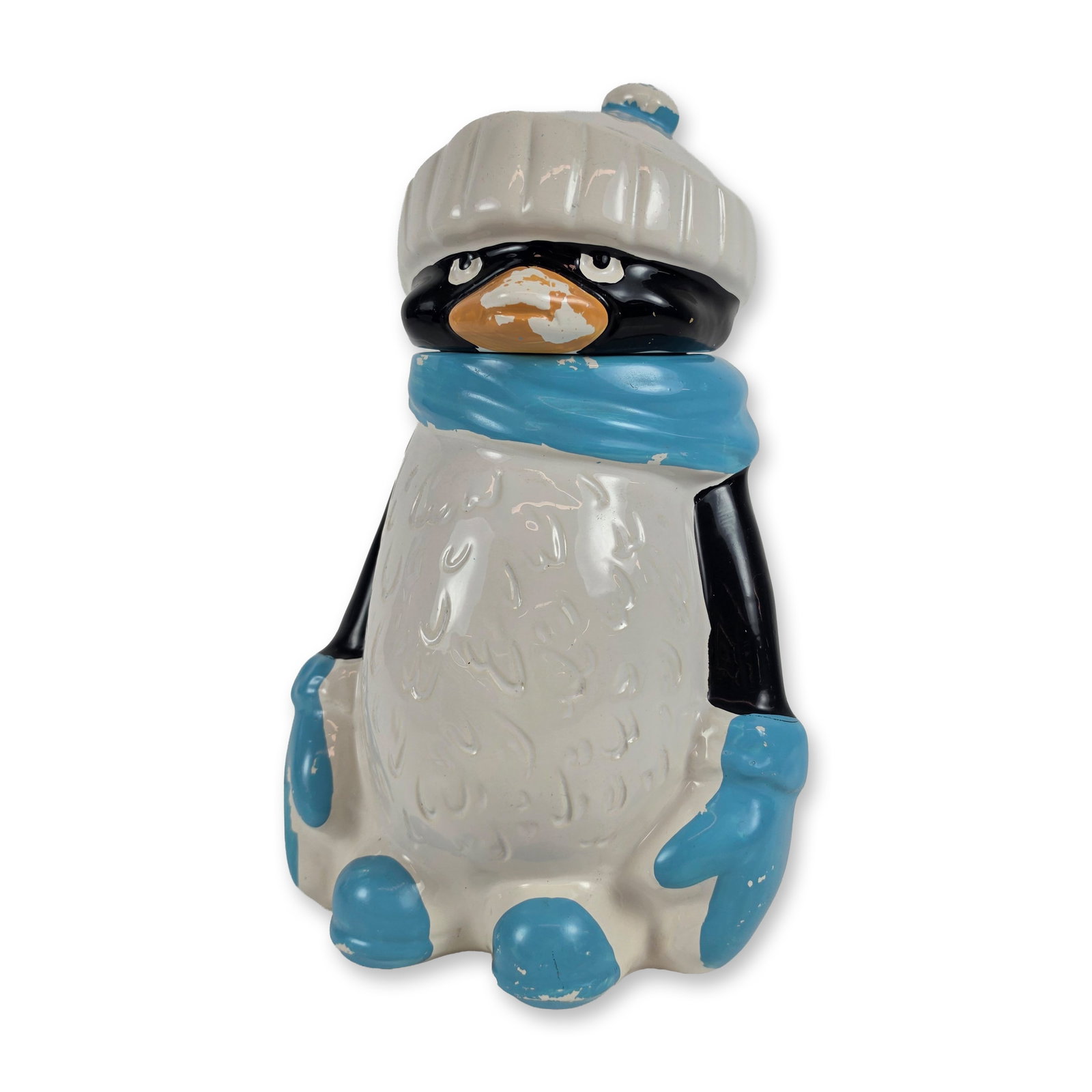 McCoy Ceramic Penguin Cookie Jar, Chilly Willy: The two-piece ceramic figure features a textured knit-style cap with a pom-pom, a scarf, mittens, and boots. The head and hat assembly serves as the removable lid. The piece is finished in black and w