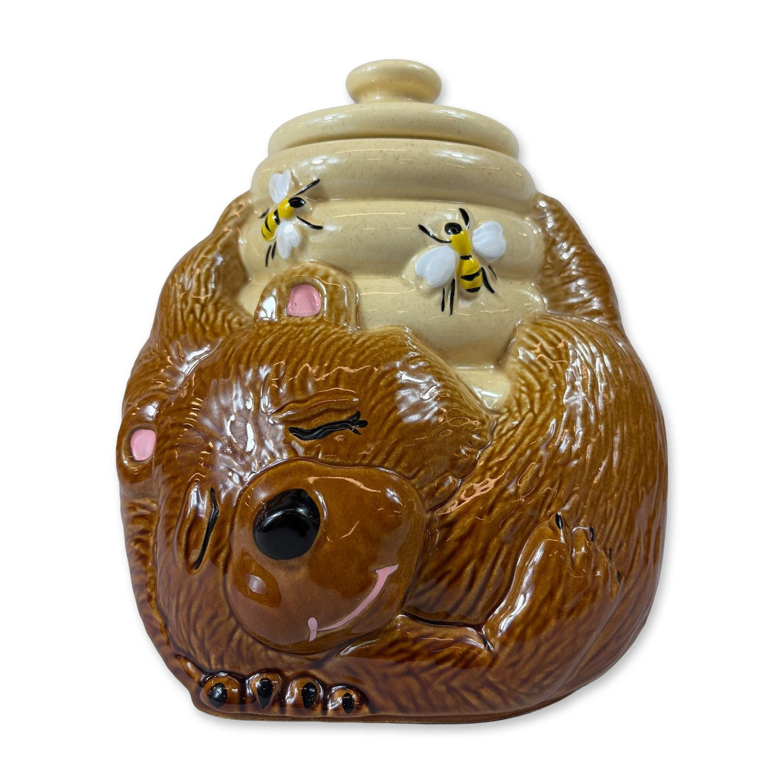 McCoy Pottery Ceramic Sleeping Bear with Beehive Cookie Jar: American ceramic figural cookie jar by McCoy Pottery. The piece is modeled as a brown bear with a textured surface clutching a yellow beehive lid. The bear features a high-gloss brown glaze with pink-