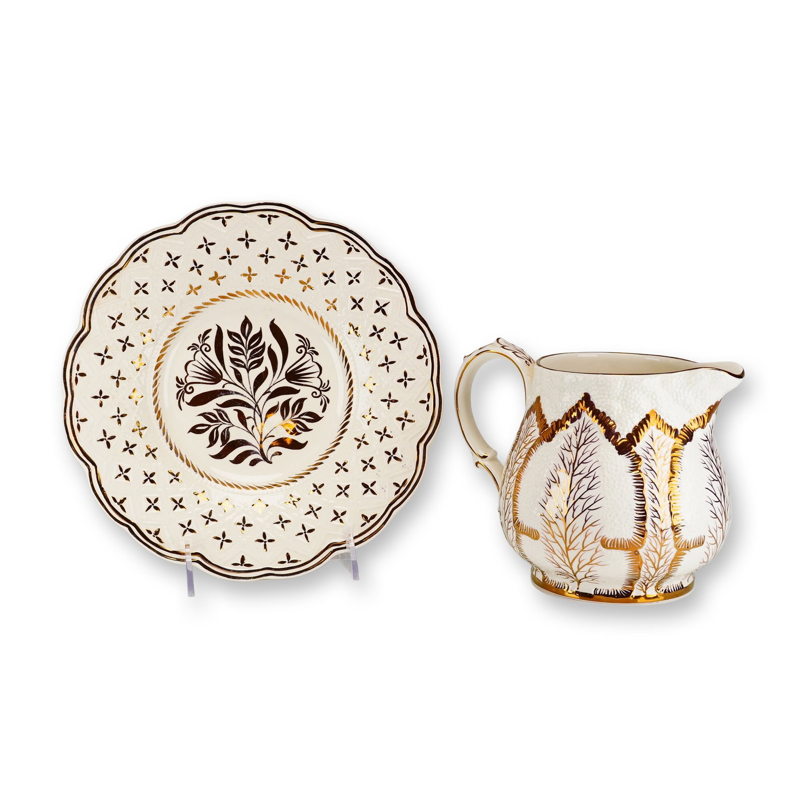 2pc Wedgwood Etruria Barlaston Gilded Trees Pattern Creamware Set: This two-piece Wedgwood creamware set includes a cream pitcher and a scalloped saucer, both featuring a stylized trees motif. The pattern is executed in dark brown transfer print with hand-applied gol