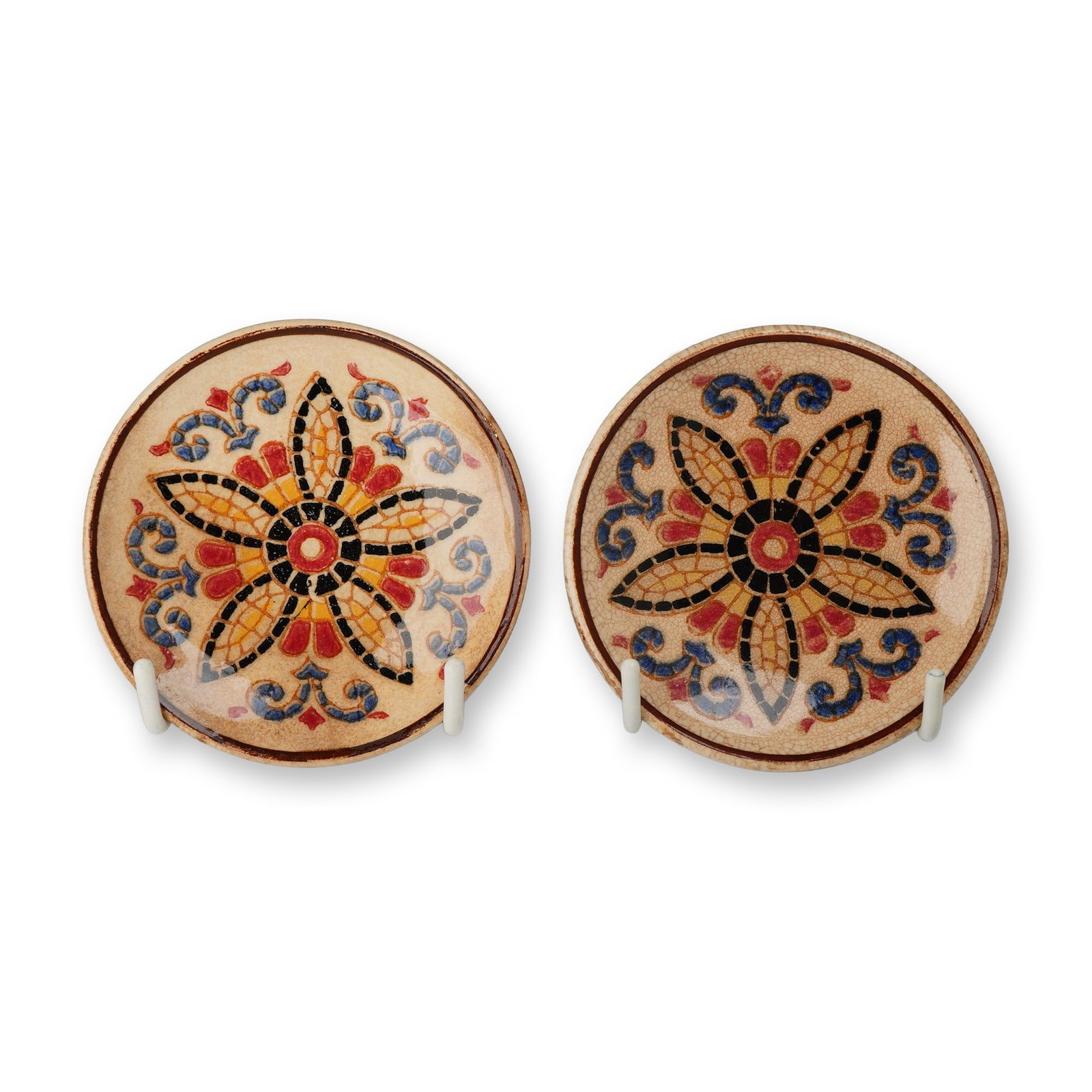 A Pair of Wedgwood Small Earthenware Dishes with Hand Painted Mosaic Style Decoration c. 1893: A pair of small, circular earthenware dishes featuring hand-painted decoration in a mosaic style. The central motif of each dish consists of a six-petaled star or flower in yellow, red, and black, sur