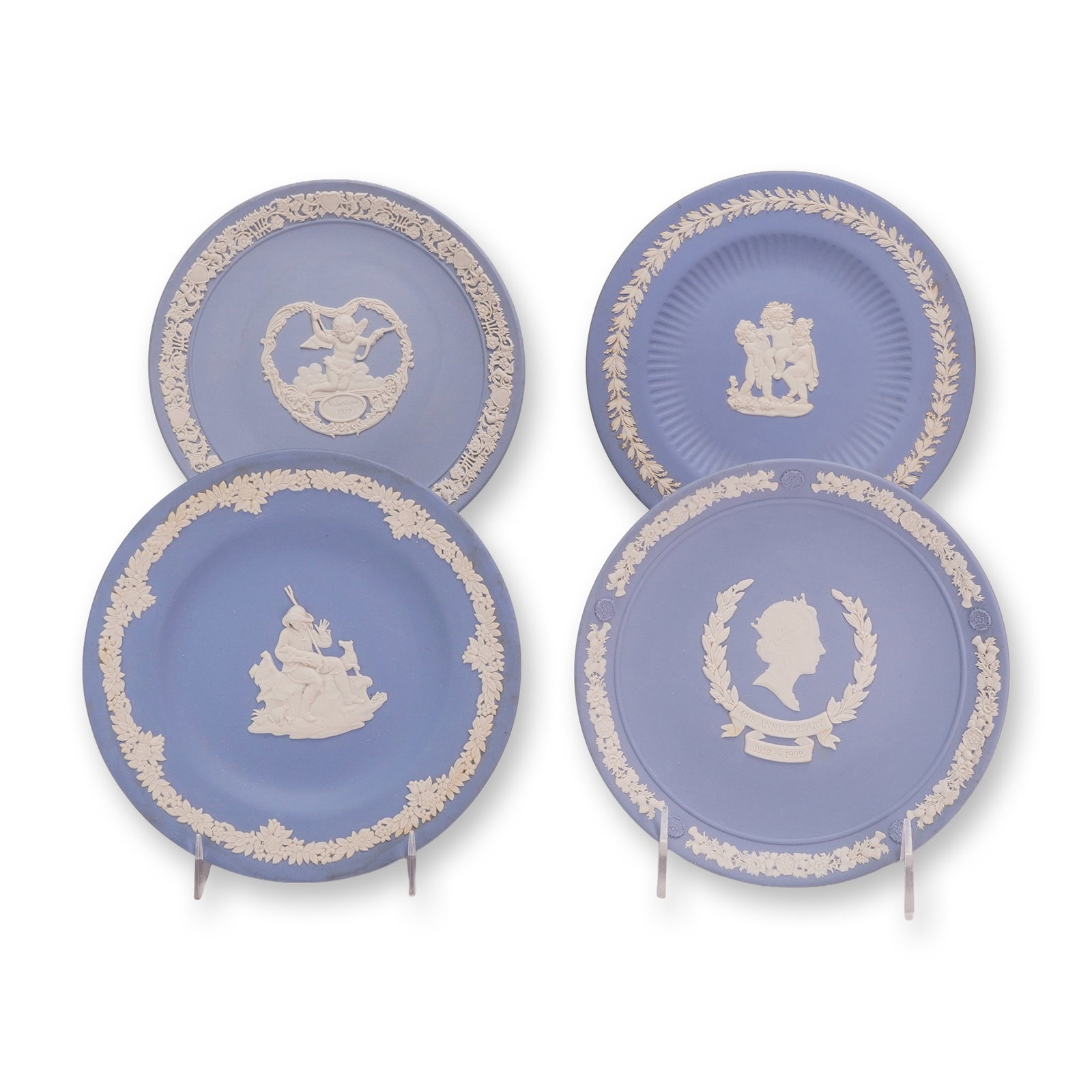 4pc Wedgwood Blue Jasperware Collector Plates: This collection of four Wedgwood blue jasperware plates features the manufacturer's signature white sprigged bas-relief decoration on a light blue unglazed stoneware ground. The group, part of the Rub