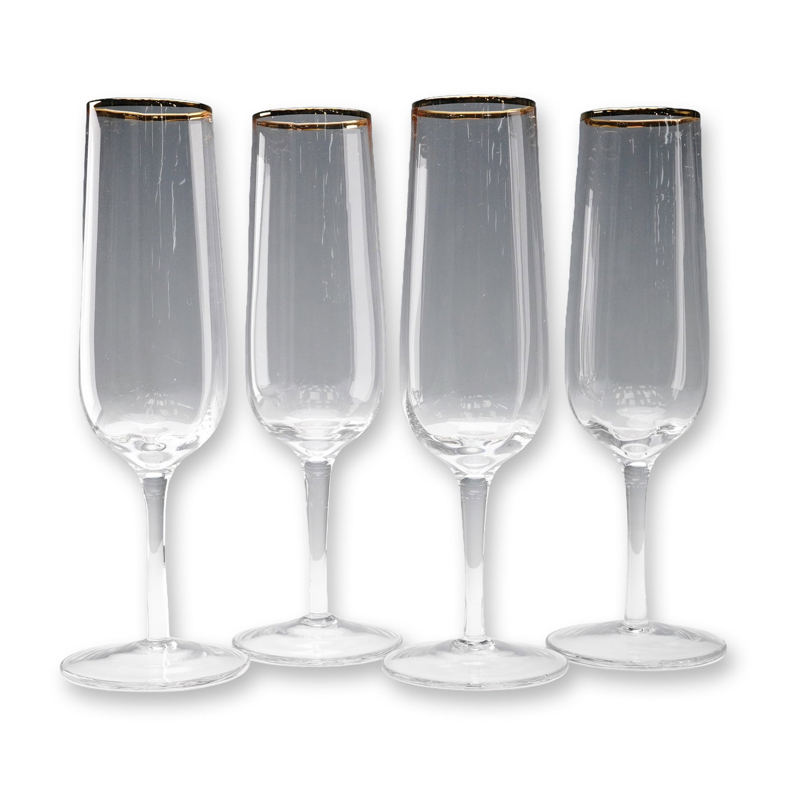 Martha Stewart Clear Champagne Flutes with Golden Rim: A refined set of four clear glass champagne flutes from the Martha Stewart collection, each featuring a slender, tapered bowl and elegantly elongated stem. The glasses are finished with a delicate met