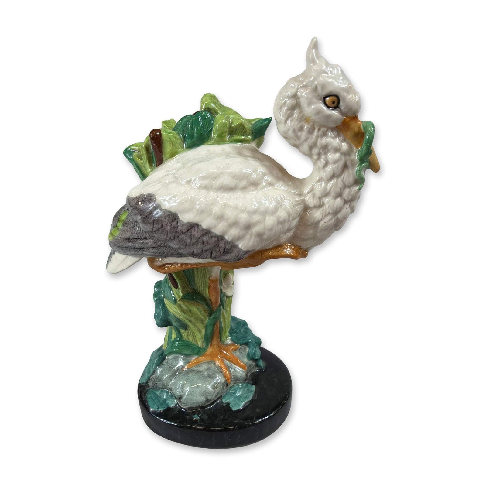 Minton Miniature Majolica Stork Figurine: A Minton in Miniature glazed porcelain figurine depicting a stork with a green snake coiled around its beak, perched amidst green reeds and brown cattails on an integral circular black base. This piec