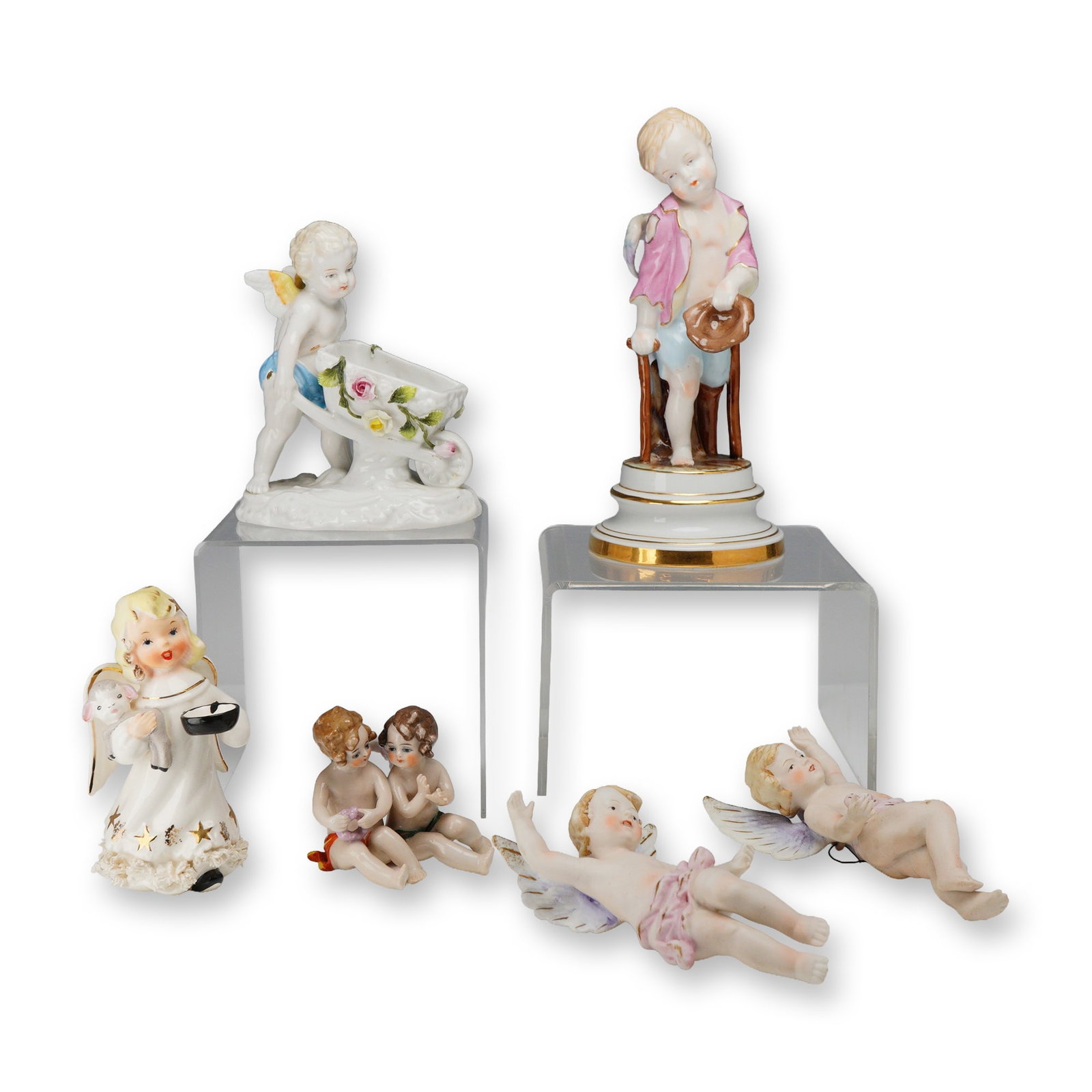 Mixed Lot of 6 Porcelain Angel and Cherub Figurines: This collection consists of six glazed and hand-painted porcelain figurines depicting various angels and cherubs. The lot includes a standing winged cherub on a circular pedestal with gold-gilt bands,