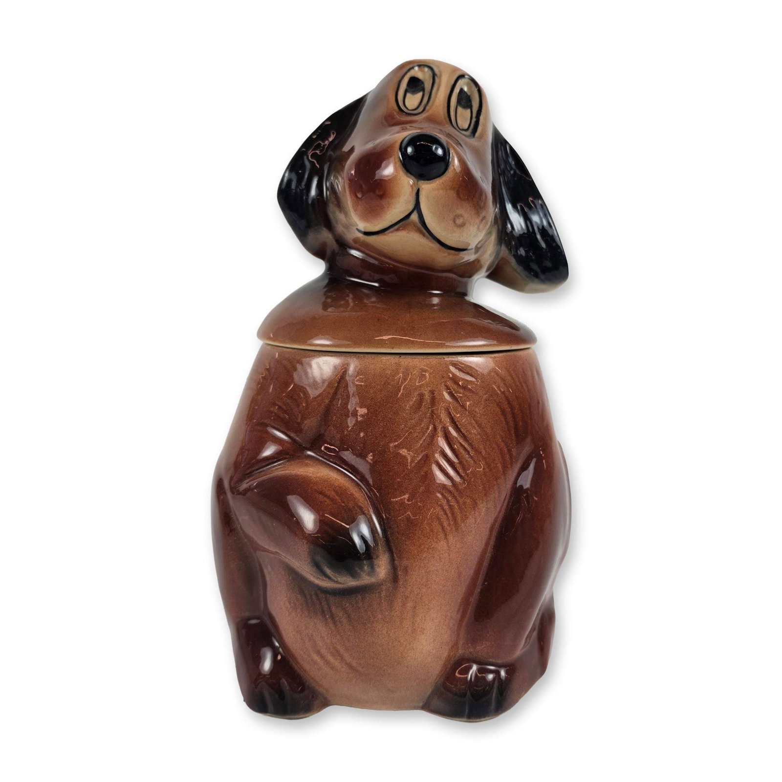 McCoy Ceramic Dog Cookie Jar: Figural cookie jar or canister in glazed earthenware, modeled as a seated puppy with floppy ears and a removable lid forming the head. The piece is finished in a glossy variegated brown and black glaz