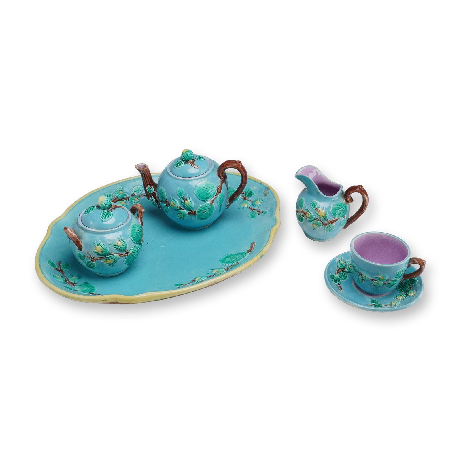 5pc Majolica Pottery Foliage Motif Tea Service Set: This ceramic majolica tea service features a vibrant turquoise blue ground decorated with relief-molded botanical motifs of green leaves and yellow blossoms on brown bark branches. The service compris
