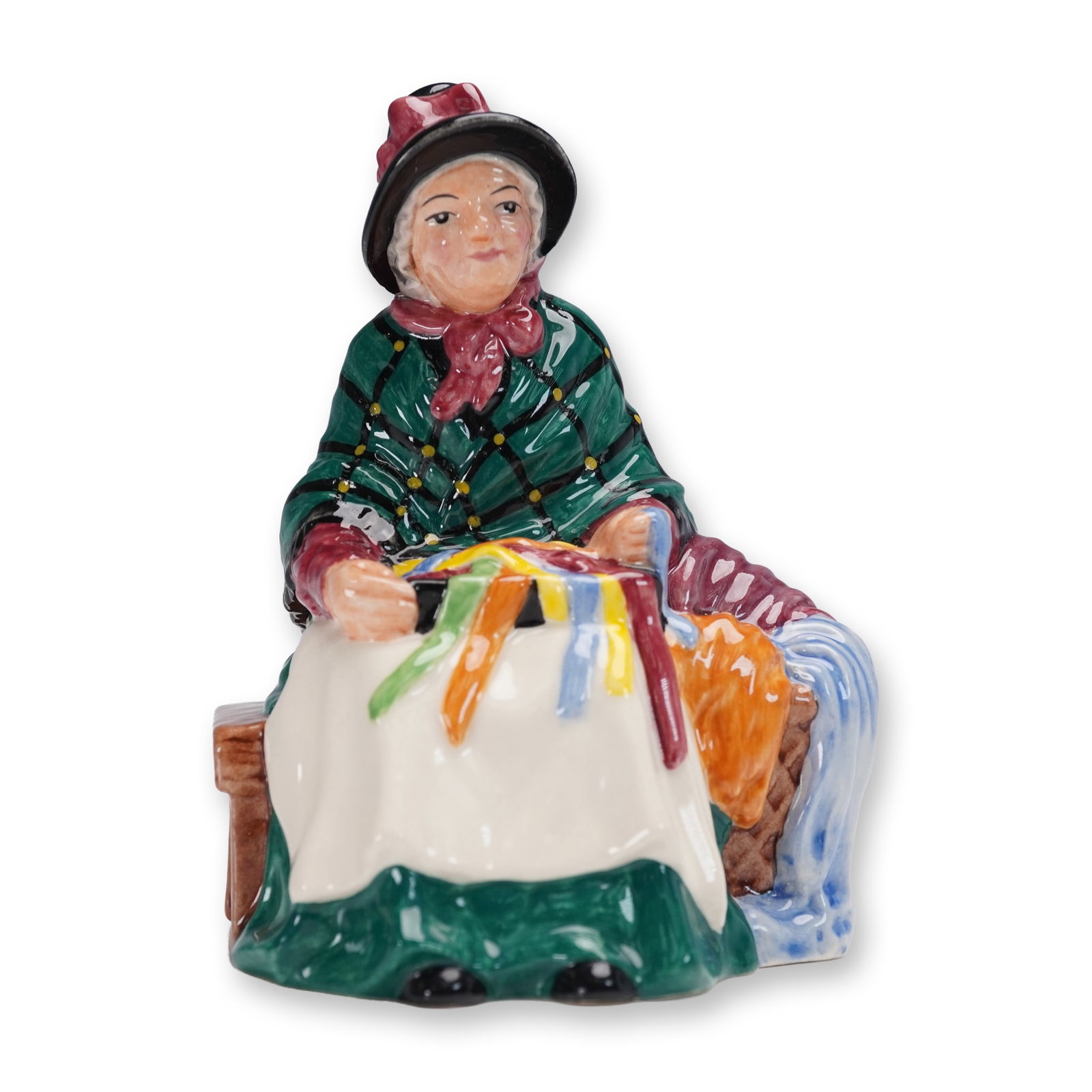 Royal Doulton Figurine, Silks & Ribbons HN4808: Issued in 2003 as part of the Miniature Street Vendors collection, this Royal Doulton figurine titled Silks & Ribbons (HN4808) captures a charming vendor arranging colorful textiles with intricate det
