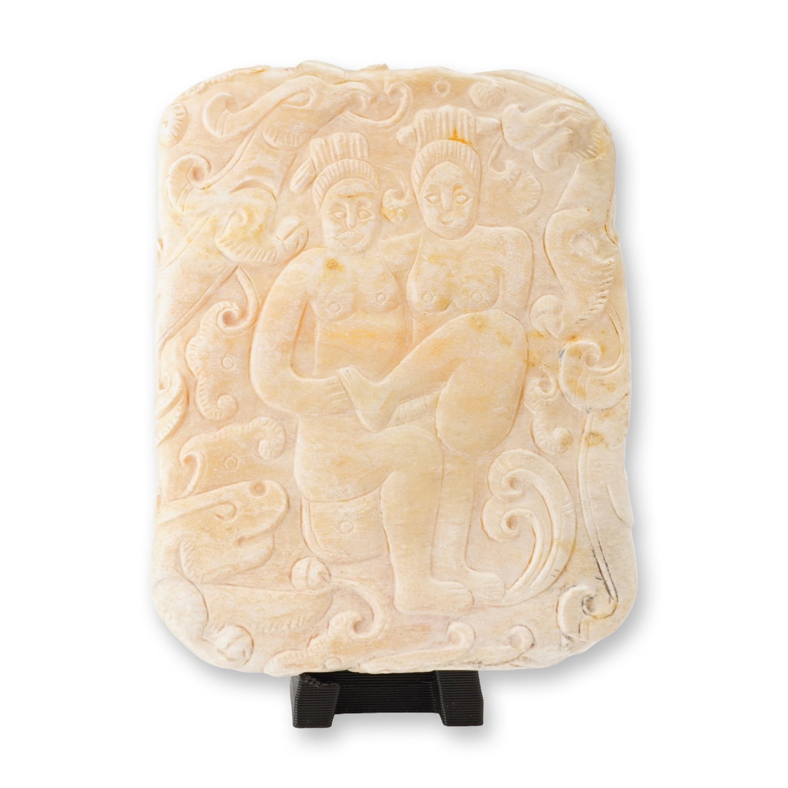 Asian Cream-Colored Stone Carved Erotic Plaque: A small carved composition depicting two nude figures in an intimate embrace, surrounded by finely detailed, flowing scrollwork ornamentation. Dimensions: 2.00"L x 2.50"H Weight: 2.80oz