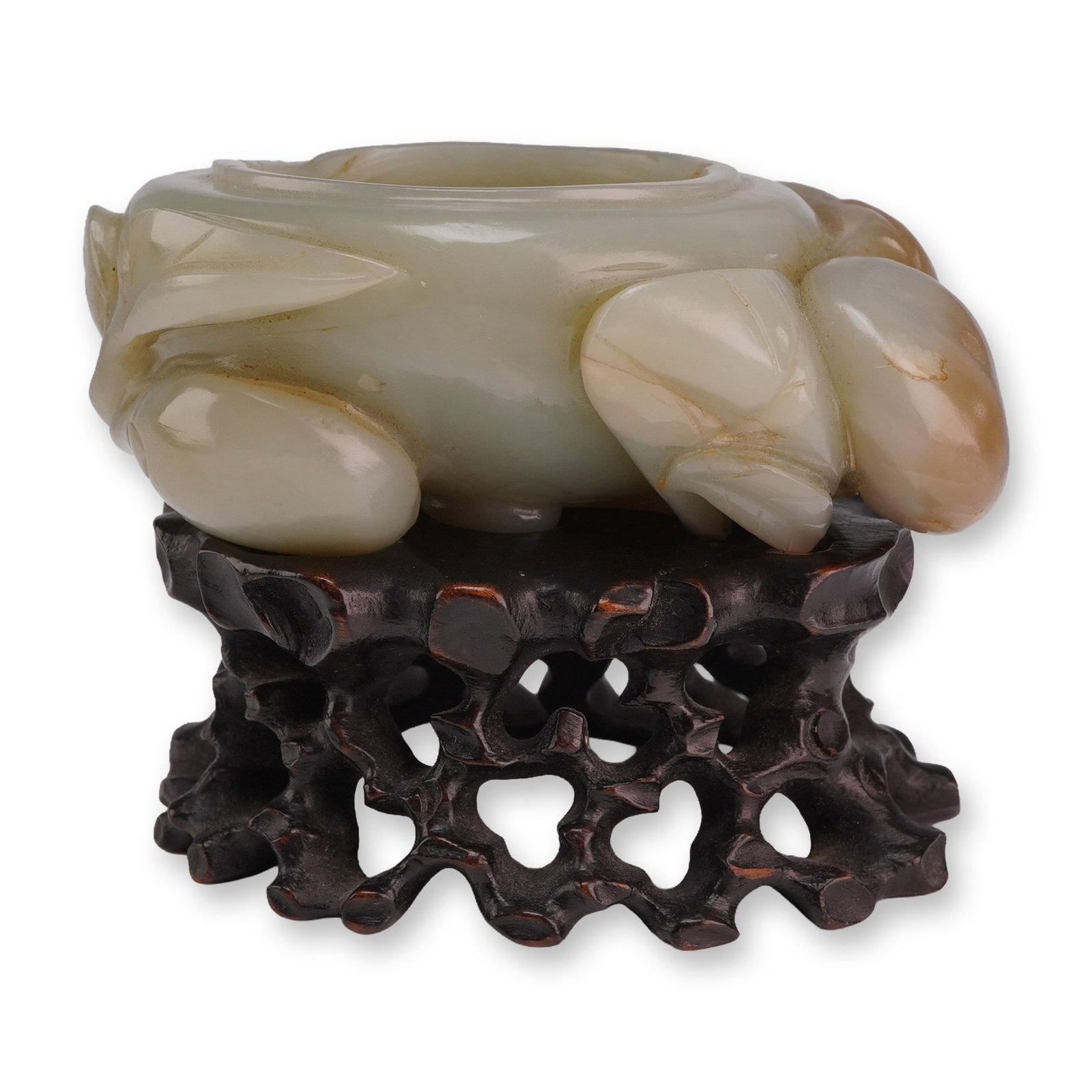 Celadon Jade Coupe and Wooden Base, Peaches Design: A small celadon jade vessel with carved peaches on leafy branches around the exterior. It is accompanied by a carved dark wooden stand. Dimensions: 3.5"L x 2.5"W x 2.5"H Weight: 11 oz