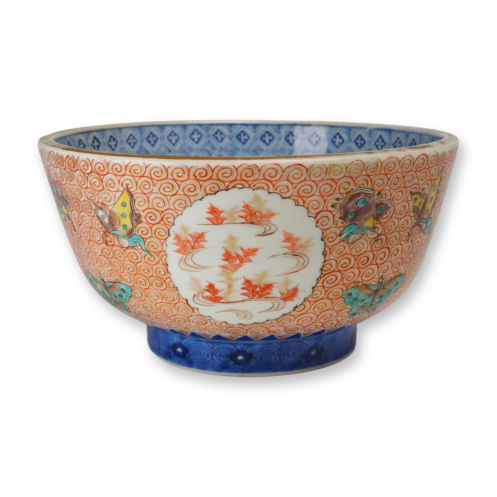 Japanese Imari Porcelain Bowl, Butterflies on Swirled Ground: A Japanese Imari porcelain bowl hand-decorated on the interior and exterior with designs including swirls, key patterns, butterflies, and flowers in shades of red, blue, and green, accented with gilt.