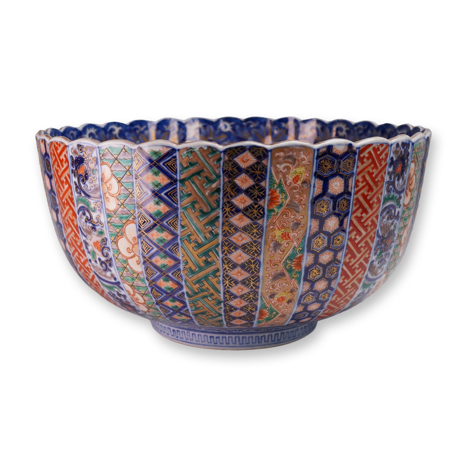 Japanese Porcelain Imari Carp and Floral Motif Bowl: Japanese Imari porcelain fluted bowl featuring alternating panels of geometric, floral, and patterned designs in polychrome enamels with gilt highlights on the exterior. The scalloped rim is bordered 