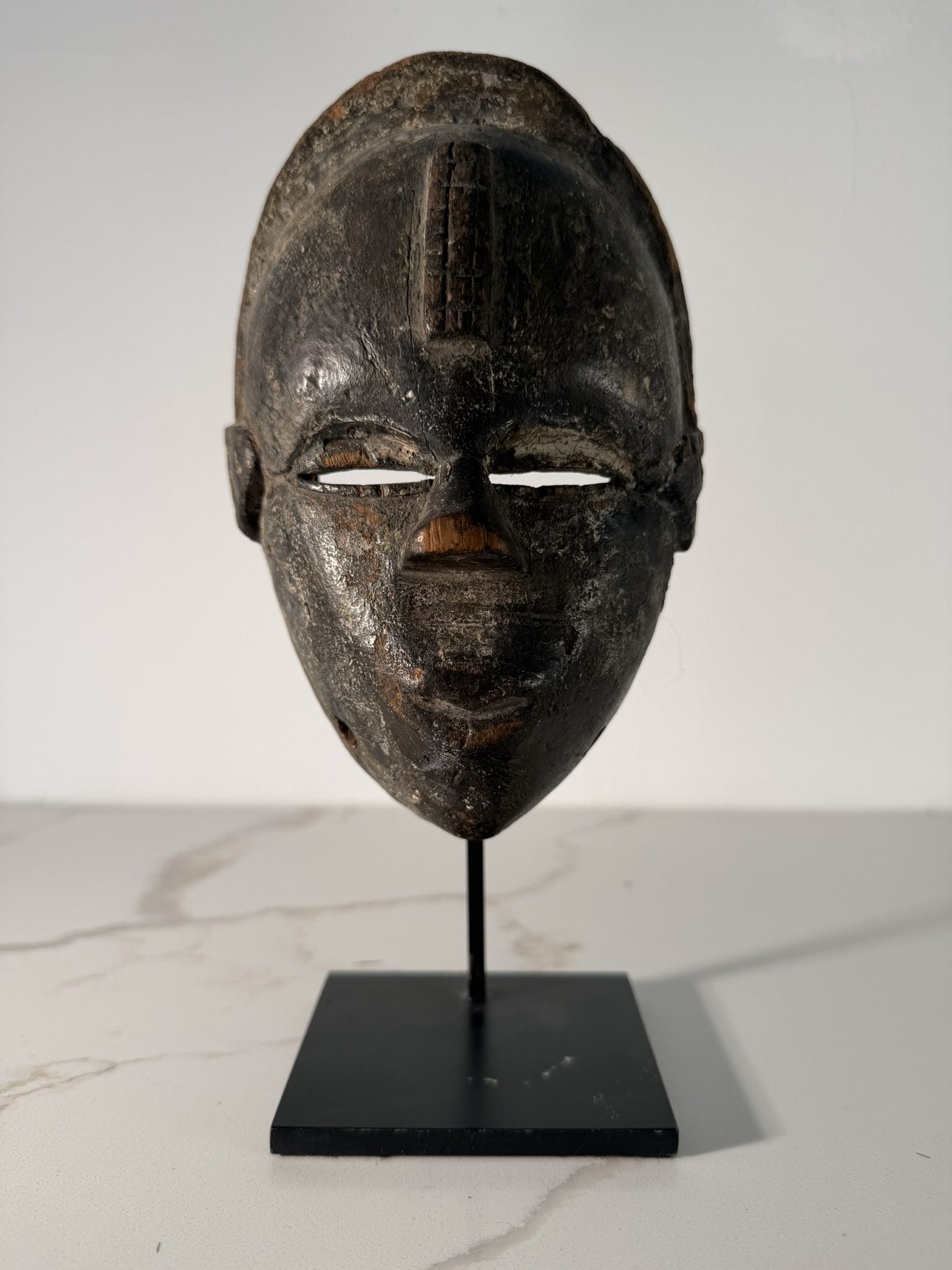 Ogoni Carved Mask, Niger Delta, Nigeria, 19th/20th Century: A carved wood Ogoni mask originating from Nigeria, specifically the Niger Delta region of southern Nigeria (Rivers State). The mask features an ovoid facial form with narrow horizontal slit eyes and a