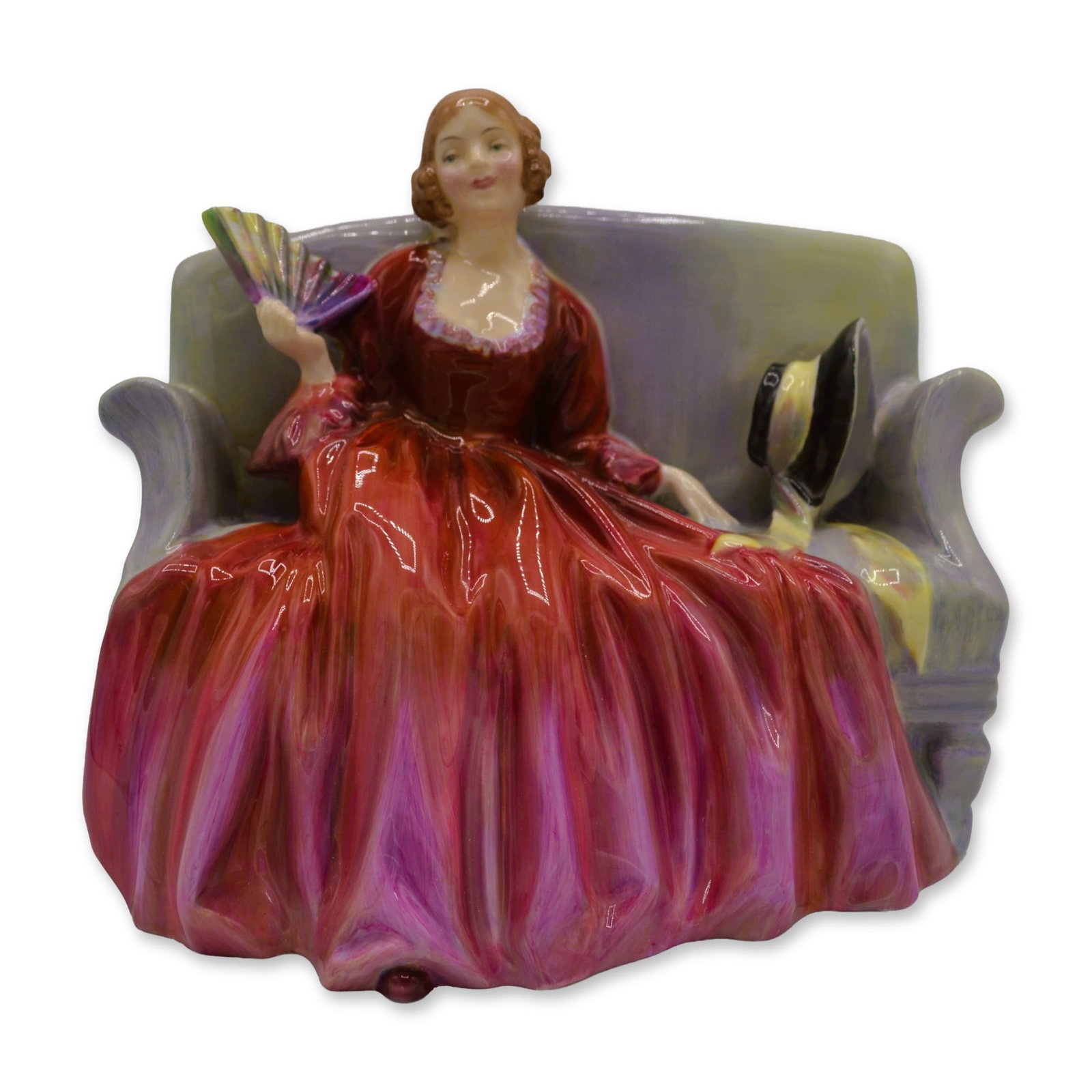 Royal Doulton Porcelain Sweet And Twenty Figurine, HN 1298: Royal Doulton Porcelain "Sweet And Twenty" Figurine, HN 1298. This Figurine depicts a young woman in the 18th Century, style long deep red dress seated on a colored settee. She holds a multi-colored f