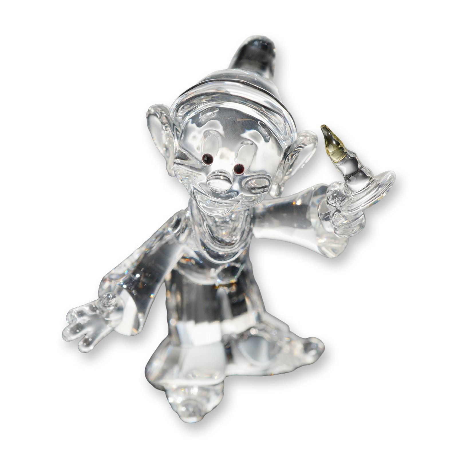Swarovski Disney Crystal Dopey Figurine: Swarovski. Disney collection Dopey figurine, model 997212, in faceted and molded lead crystal. The character is depicted in a cheerful pose featuring jet black crystal eyes, a faceted light yellow cry