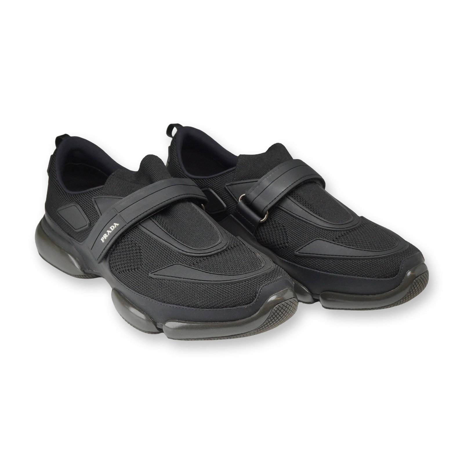 Prada Black Knit Cloudbust Strap Sneakers: Prada low-top Cloudbust knit strap sneakers, style code 2OG064, in black mesh textile with tonal rubber overlays, a hook-and-loop strap closure across the vamp, and a chunky segmented rubber platform 