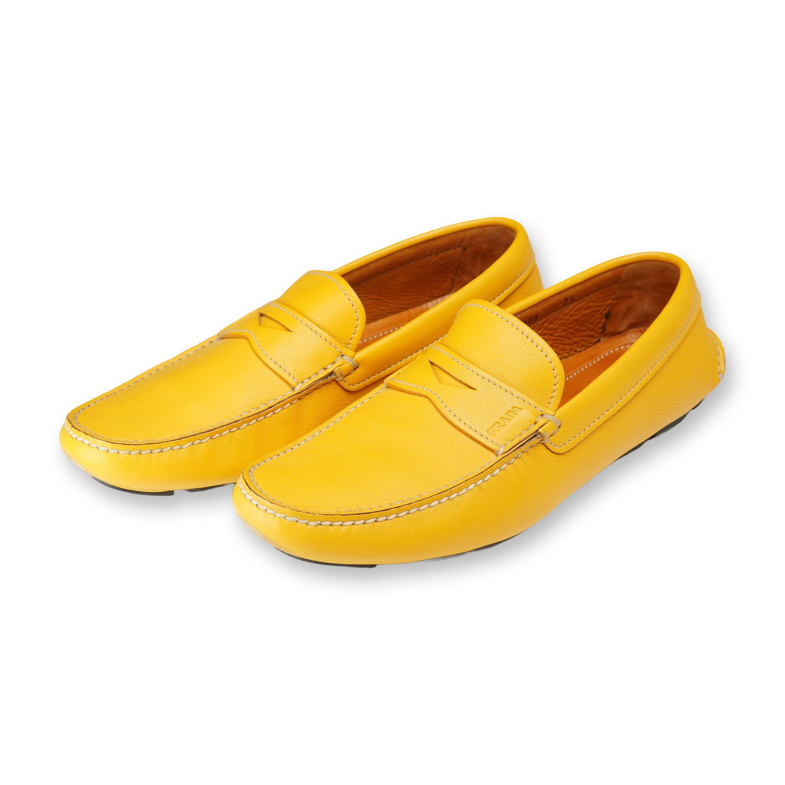 Pair of Prada Mustard Yellow Leather Loafers: Prada driving loafers in mustard yellow grained leather, style 2DD 001. Features a classic penny loafer strap across the vamp, moc-toe stitching, and a segmented rubber pod outsole. The interior is li