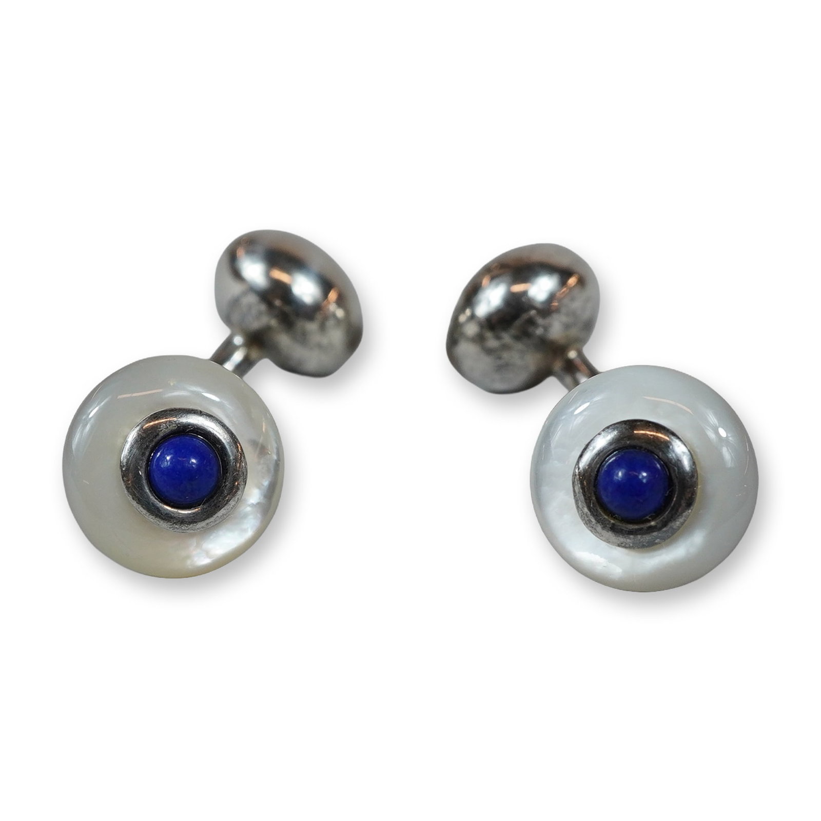 2pc Art Deco Sterling Silver Lapis and Mother-of-Pearl Cufflinks: This British Art Deco pair of double-sided barbell-style cufflinks is crafted in sterling silver and features circular faces inlaid with iridescent mother-of-pearl and centered with bezel-set lapis la