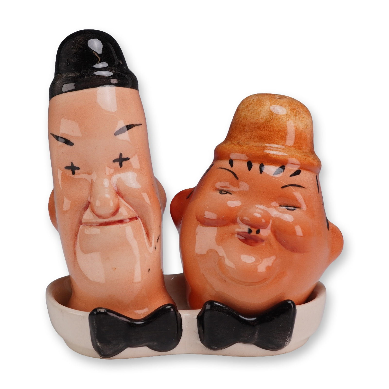 Beswick Ceramic Shaker Set, Laurel and Hardy: A figural salt and pepper shaker set in glazed earthenware, featuring caricatures of the comic duo Laurel and Hardy. The set comprises two figural head shakers and a coordinating double-well display s
