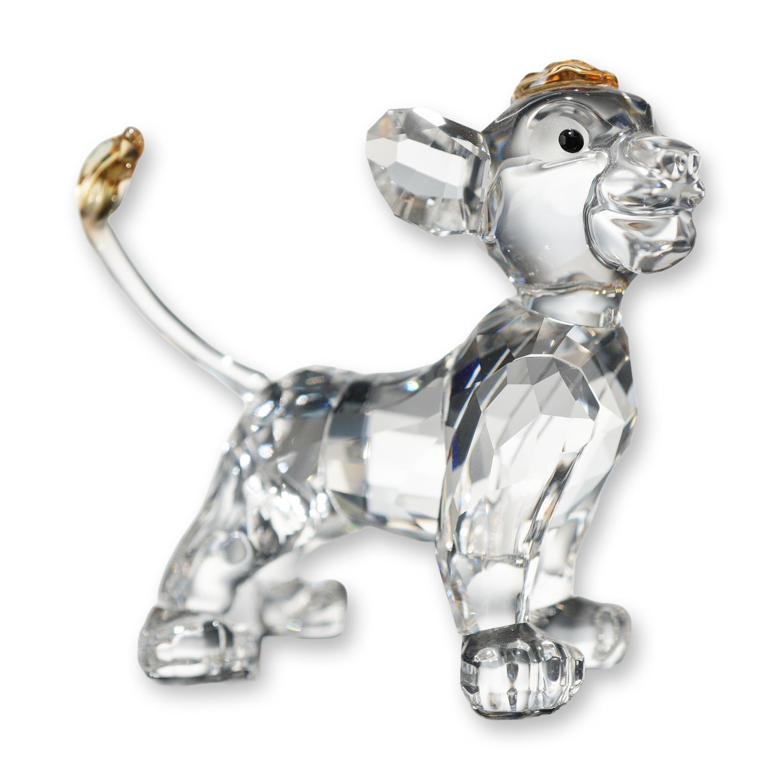 Swarovski Crystal Simba Disney Figurine: Swarovski crystal figurine depicting the character Simba from Disney's The Lion King. The figure is crafted from faceted clear crystal with black crystal eyes and amber-colored crystal accents to the 