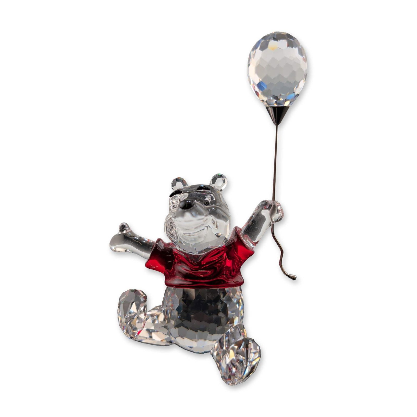 Swarovski Disney Winnie the Pooh Crystal Figurine: Swarovski Disney collection Winnie the Pooh with Balloon crystal figurine. Composed of faceted clear and red crystal, the figure is depicted in a dynamic pose holding a silver-tone metal wire topped w