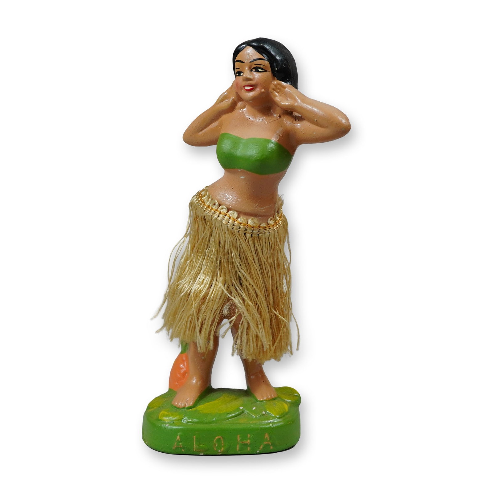 Vintage Japanese Ceramic Aloha Hawaiian Dancing Hula Girl Figurine: Mid-century Japanese souvenir figurine depicting a Hawaiian hula girl in a dancing pose. The figure is constructed of painted ceramic, featuring a natural raffia fiber grass skirt and a green bandeau 