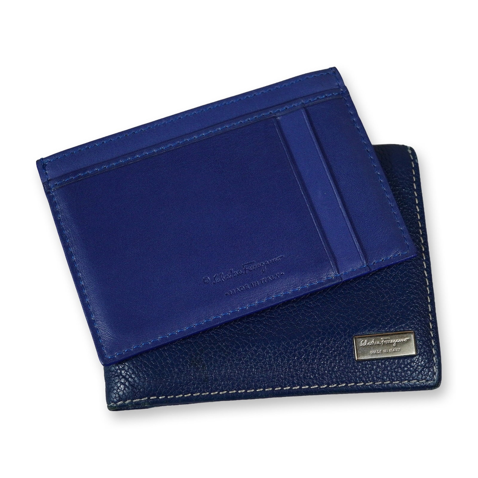 Two Salvatore Ferragamo Leather Wallets: Salvatore Ferragamo. Two wallets in leather, including a blue bifold and a blue card wallet with blue stitching. The bifold is crafted from navy blue pebbled leather featuring white contrast perimeter