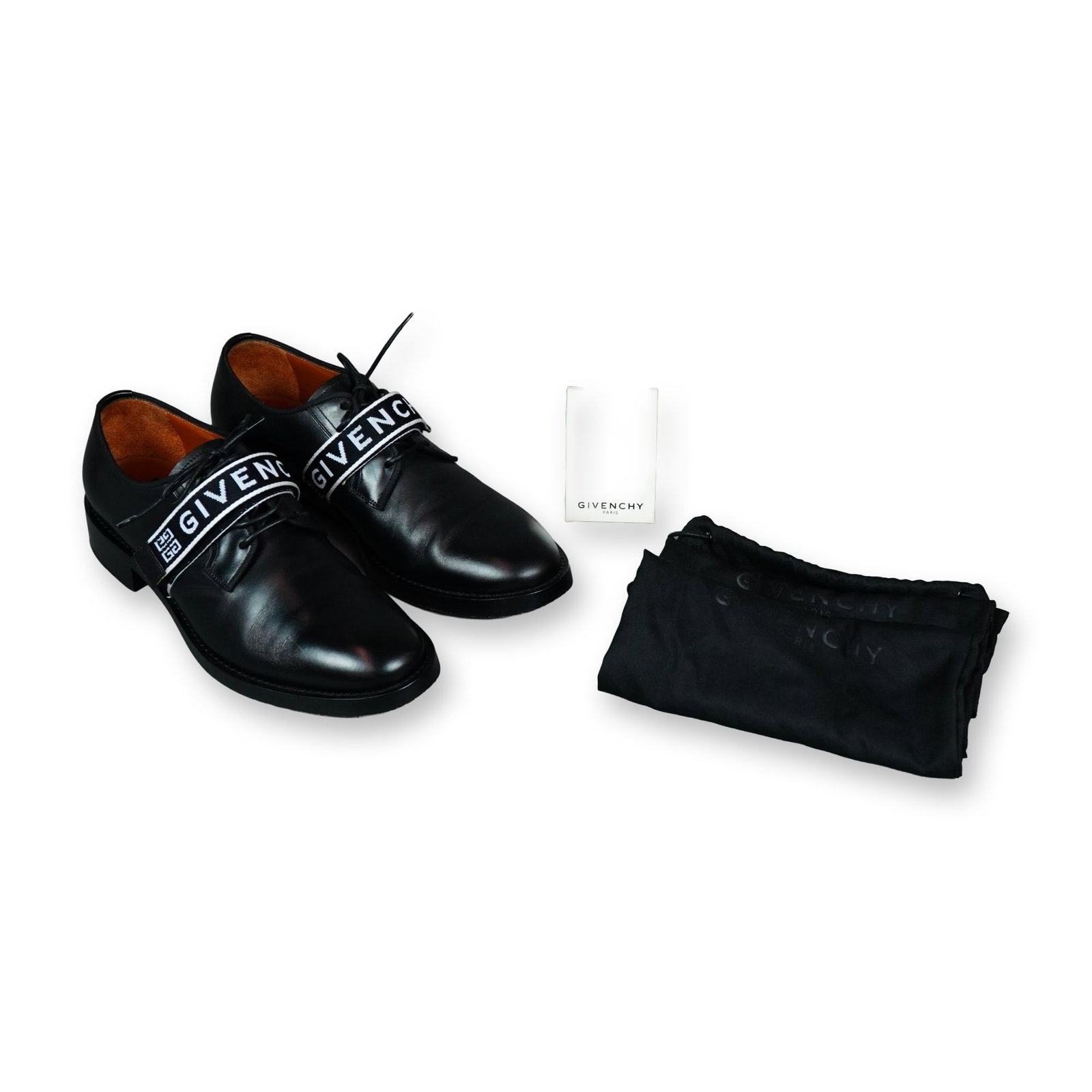Givenchy Cruz Black Leather Derby Shoes: Givenchy Cruz Derby shoes in black leather, featuring a signature midfoot hook-and-loop elastic strap woven with high-contrast Givenchy lettering and the geometric 4G motif. The lace-up shoes are cons