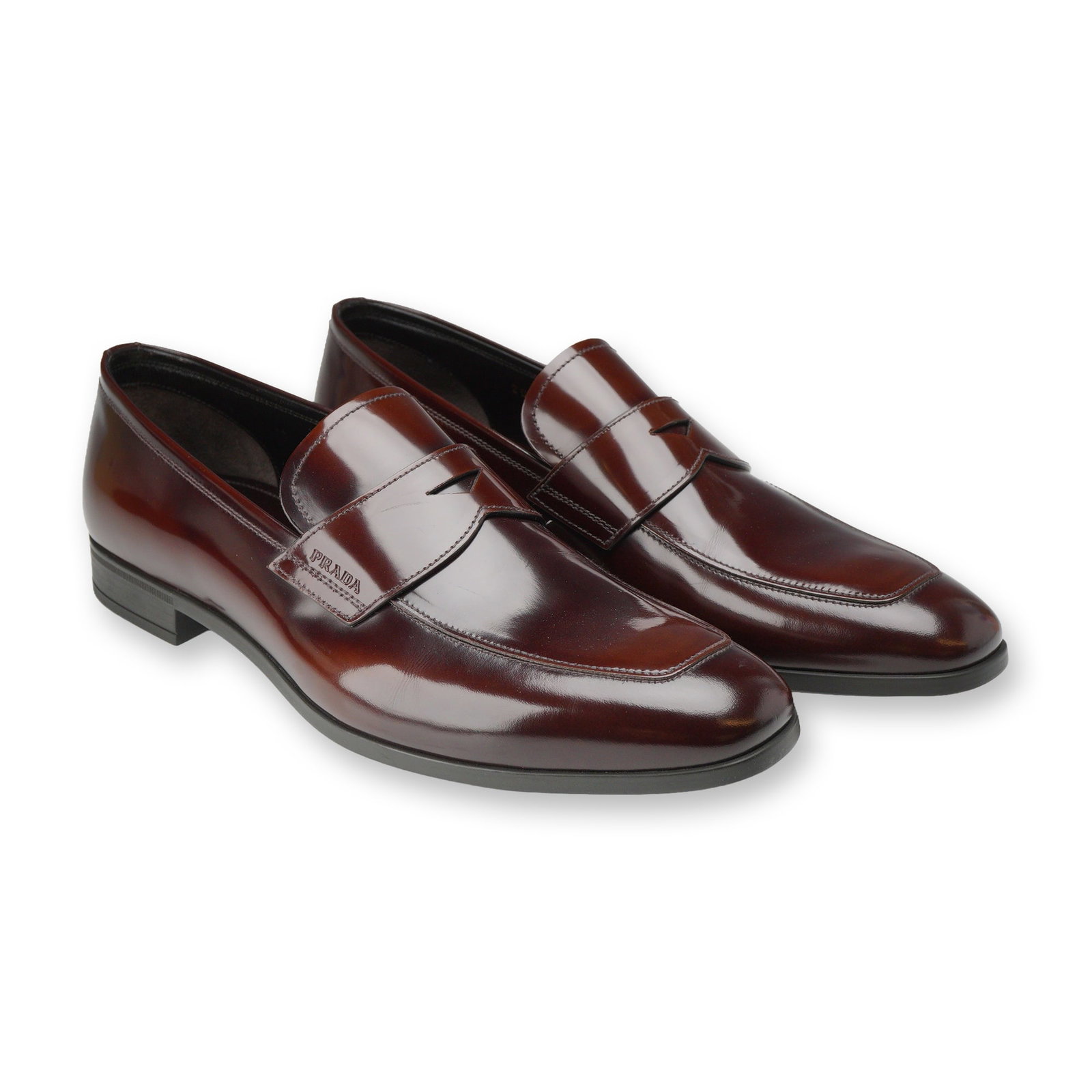 Pair of Prada Brown Leather Penny Loafers: Prada, Italy. Pair of men's penny loafers in polished brown leather, model 2DC145. Constructed with classic penny keeper straps, stitched moc toe detailing, and leather linings. Fitted with composite 