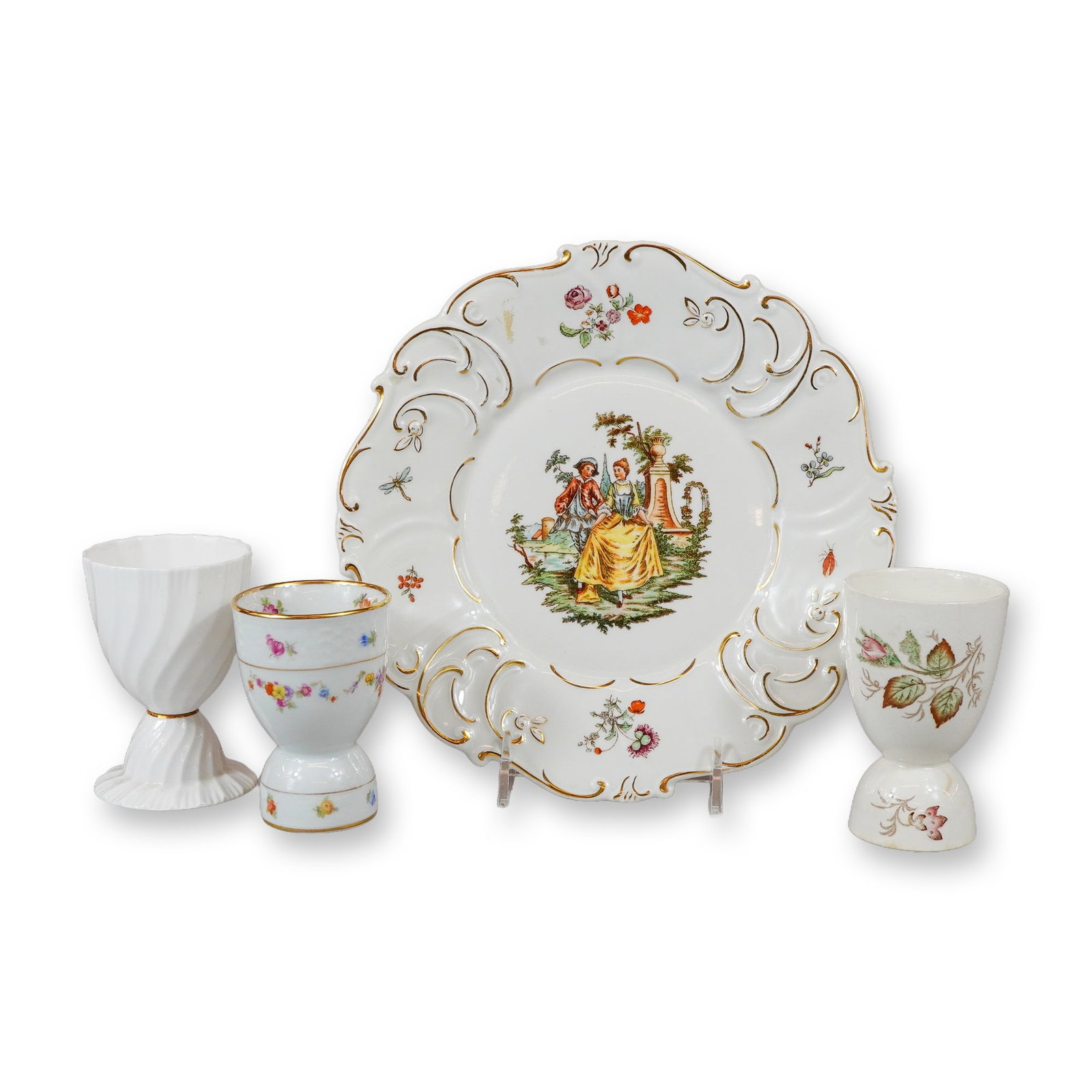 4pc Porcelain Grouping Including Wallendorf Plate and Three Assorted Egg Cups: A four-piece grouping of decorative porcelain featuring a cabinet plate and three assorted pedestal egg cups. The collection includes a Wallendorf (Germany) cabinet plate with a deeply scalloped and m
