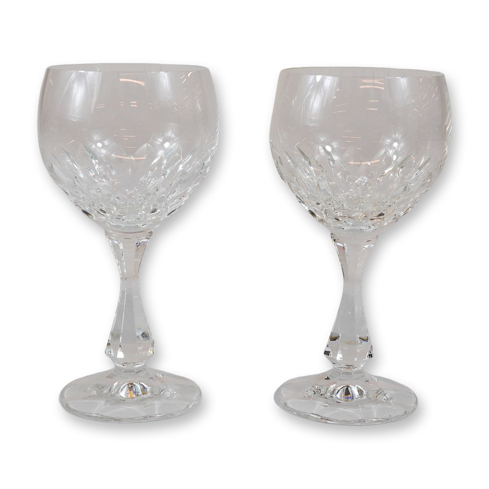 Pair of Cut Crystal Decorated Wine Glasses with Faceted Stems: A set of two matching wine glasses crafted from lead crystal. The bowls are designed with a clear upper portion and a decorative lower section featuring deep crisscross or diamond-shaped cuts. The