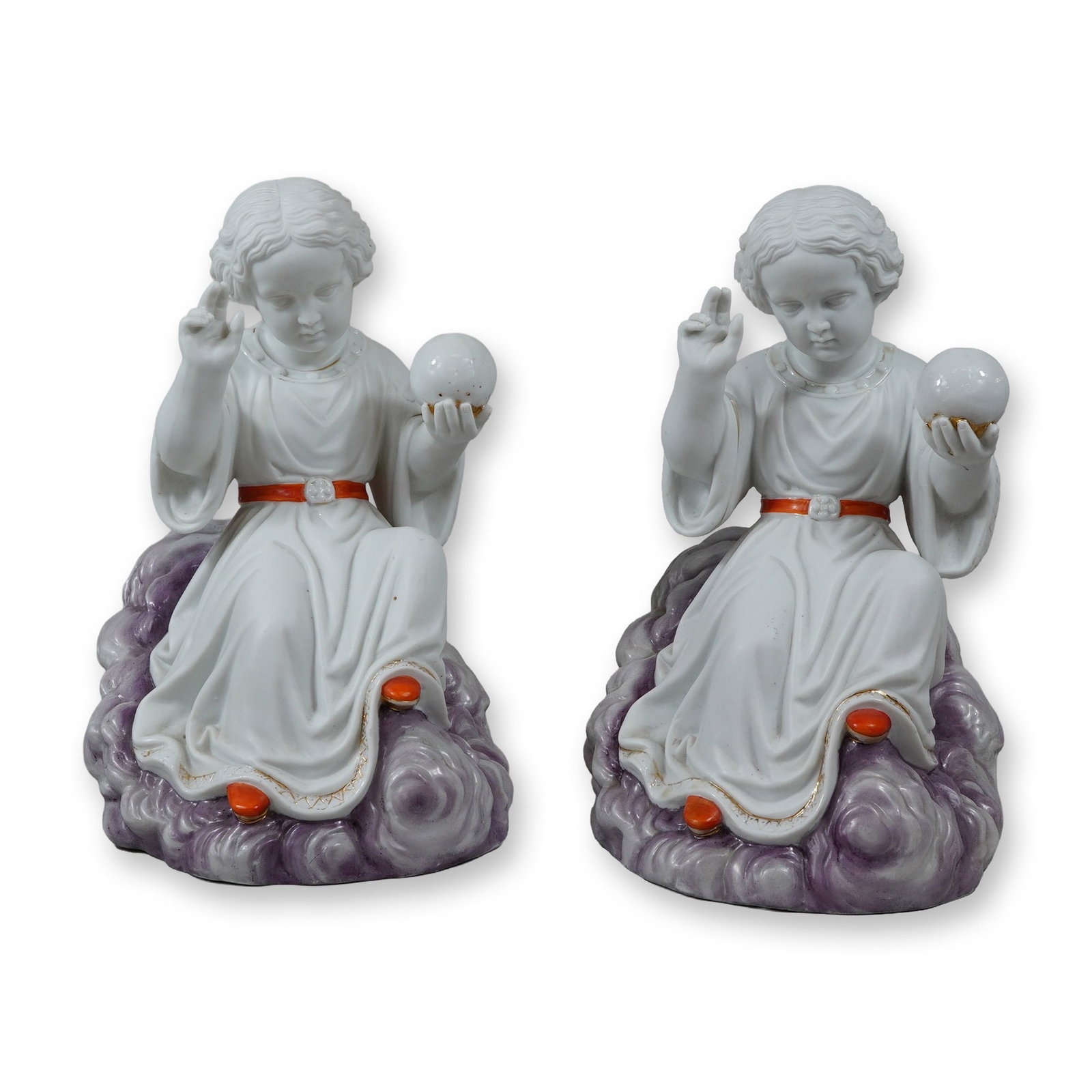 A Pair of Porcelain Figurines Depicting the Child Jesus as Salvator Mundi: A pair of glazed porcelain figurines depicting the Child Jesus as the Salvator Mundi. Each figure is depicted seated atop a billowing cloud base accented with a soft lavender-purple wash. The Christ