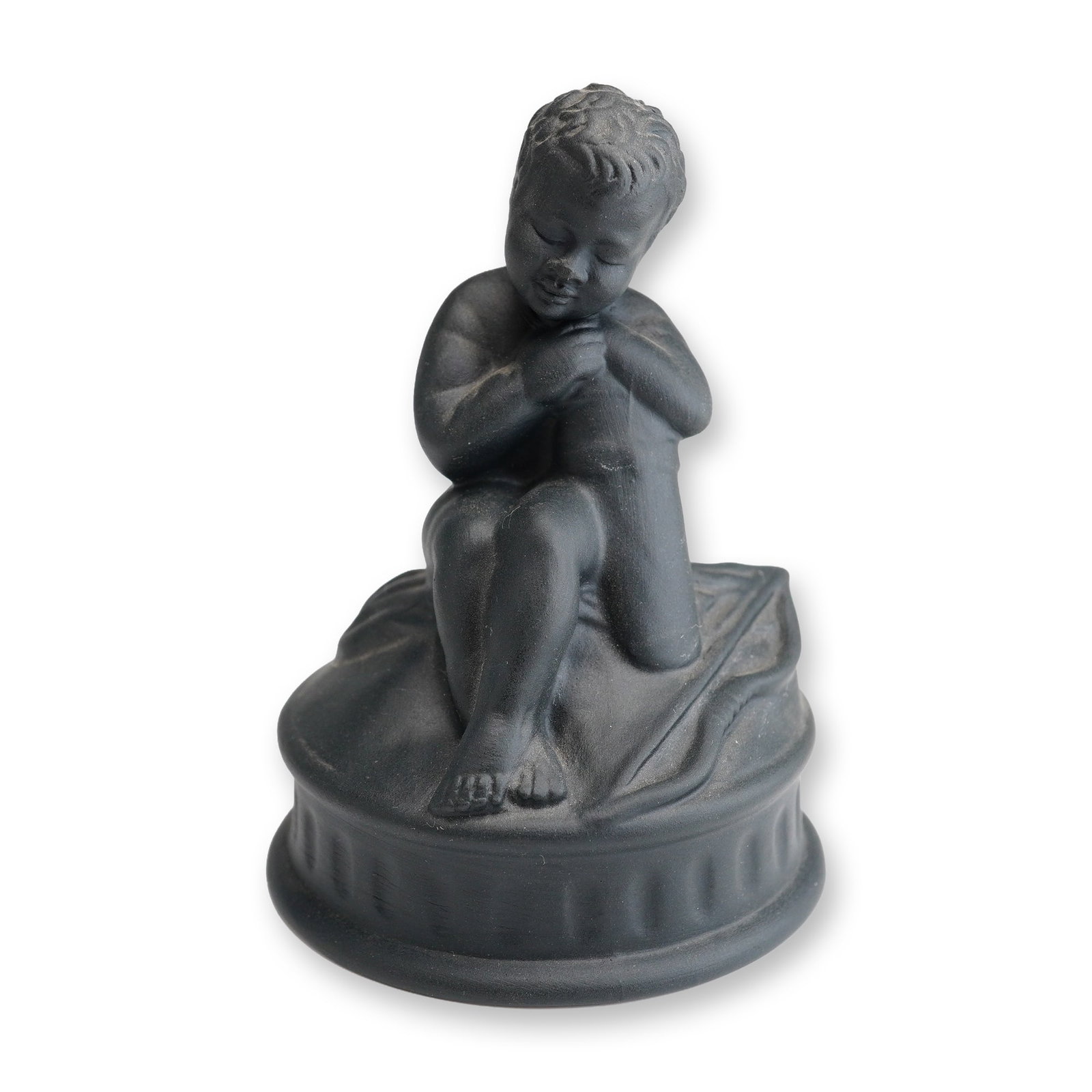 Wedgwood Black Basalt Seated Cherub Figurine: A 20th-century Wedgwood black basalt stoneware figurine depicting a seated cherub in a pensive or contemplative pose. The figure is modeled with hands clasped and head resting upon them, seated on a c