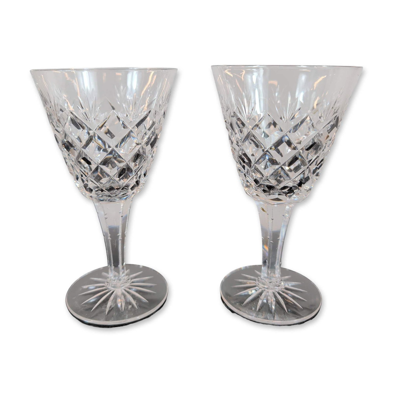 Pair of Crystal Wine Glasses: Pair of wine glasses, crafted in lead crystal. The bowls feature a lower band of deep-cut diamond patterns surmounted by vertical wedge cuts. The six-sided faceted stems lead to circular feet