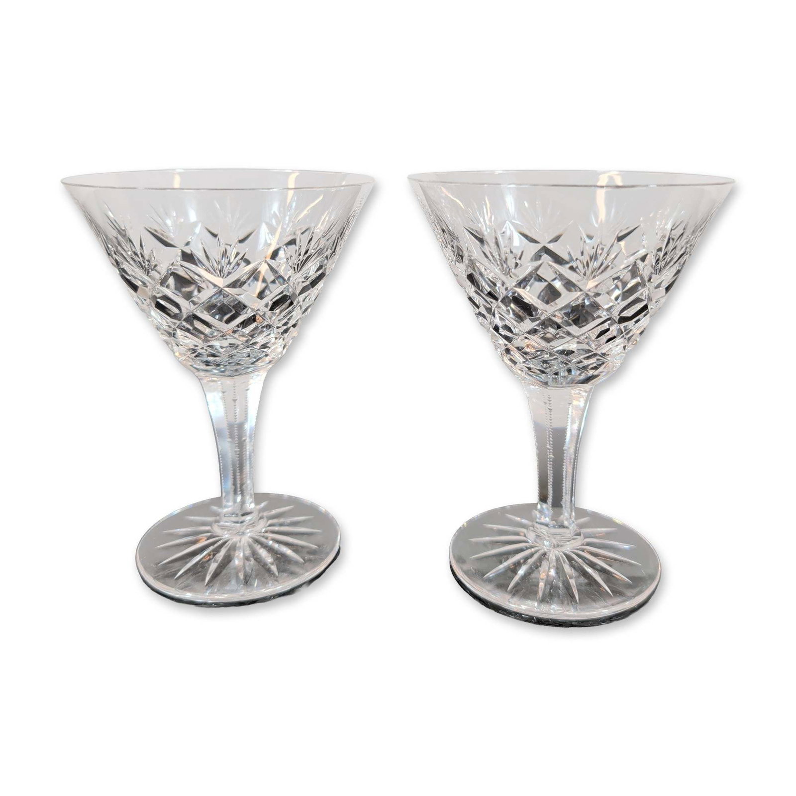 Pair of Cut Crystal Champagne Glasses: Pair of cocktail glasses, crafted from cut lead crystal. The bowls feature deep-cut criss-cross diamond motifs around the base, surmounted by vertical fan cuts toward the rims. Stems are
