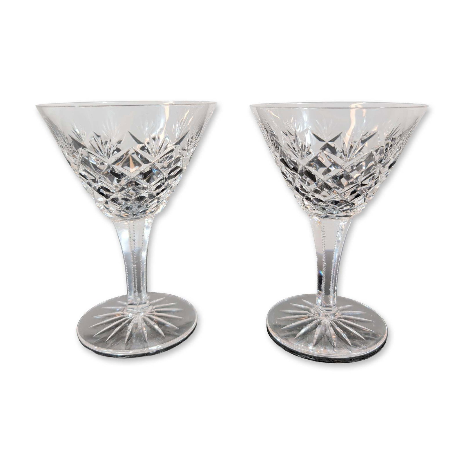 Pair of Cut Crystal Stemmed Coupes: A pair of cut crystal stemmed goblets featuring a classic cut design. Each goblet features a flared bowl decorated with a central band of deep diamond-cut cross-hatching surmounted by a row of