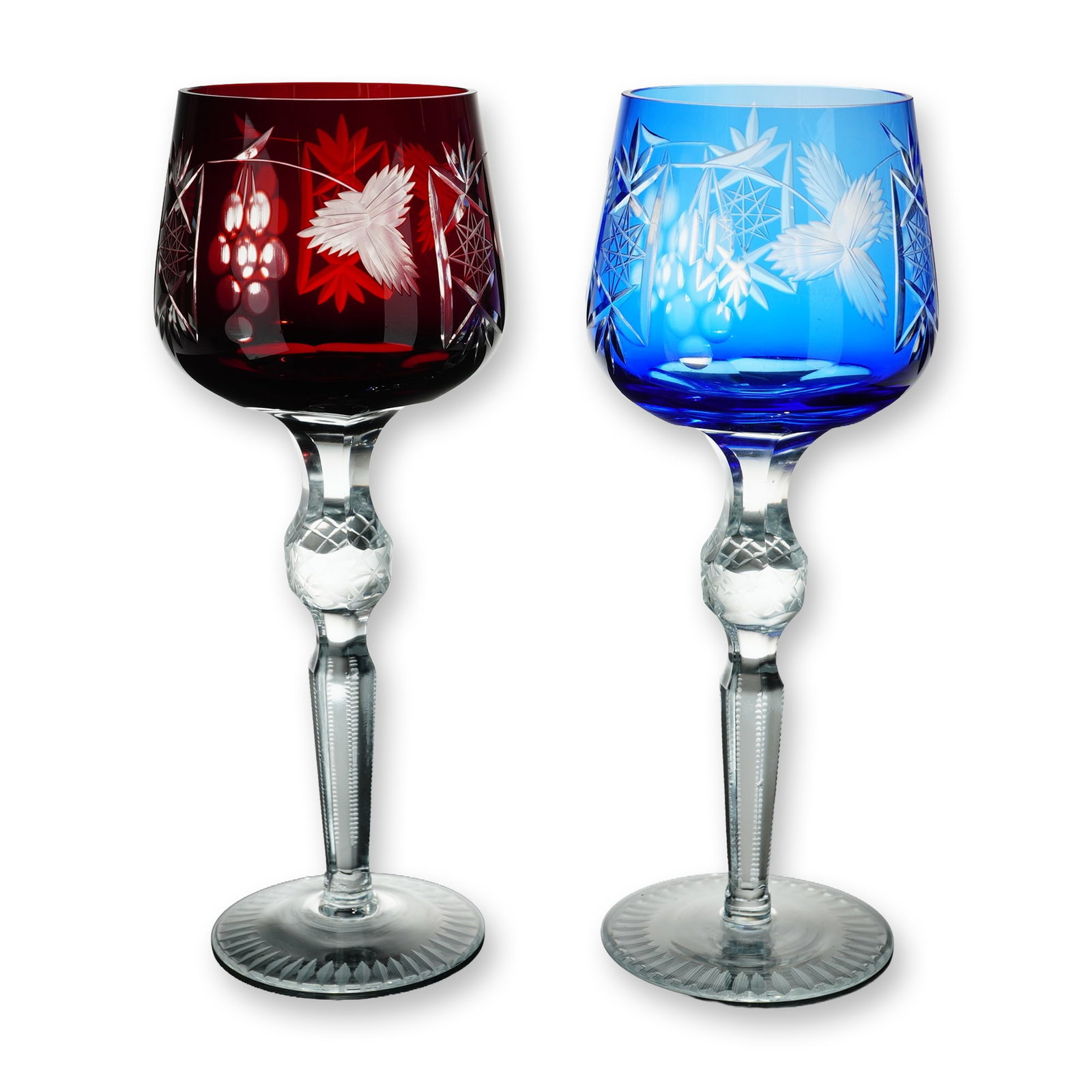 2pc Bohemian Cut-to-Clear Crystal Hocks: Bohemian style. Pair of hock wine glasses in cut-to-clear crystal, featuring one ruby red and one cobalt blue bowl decorated with grape clusters, frosted three-lobed leaves, and geometric star motifs.